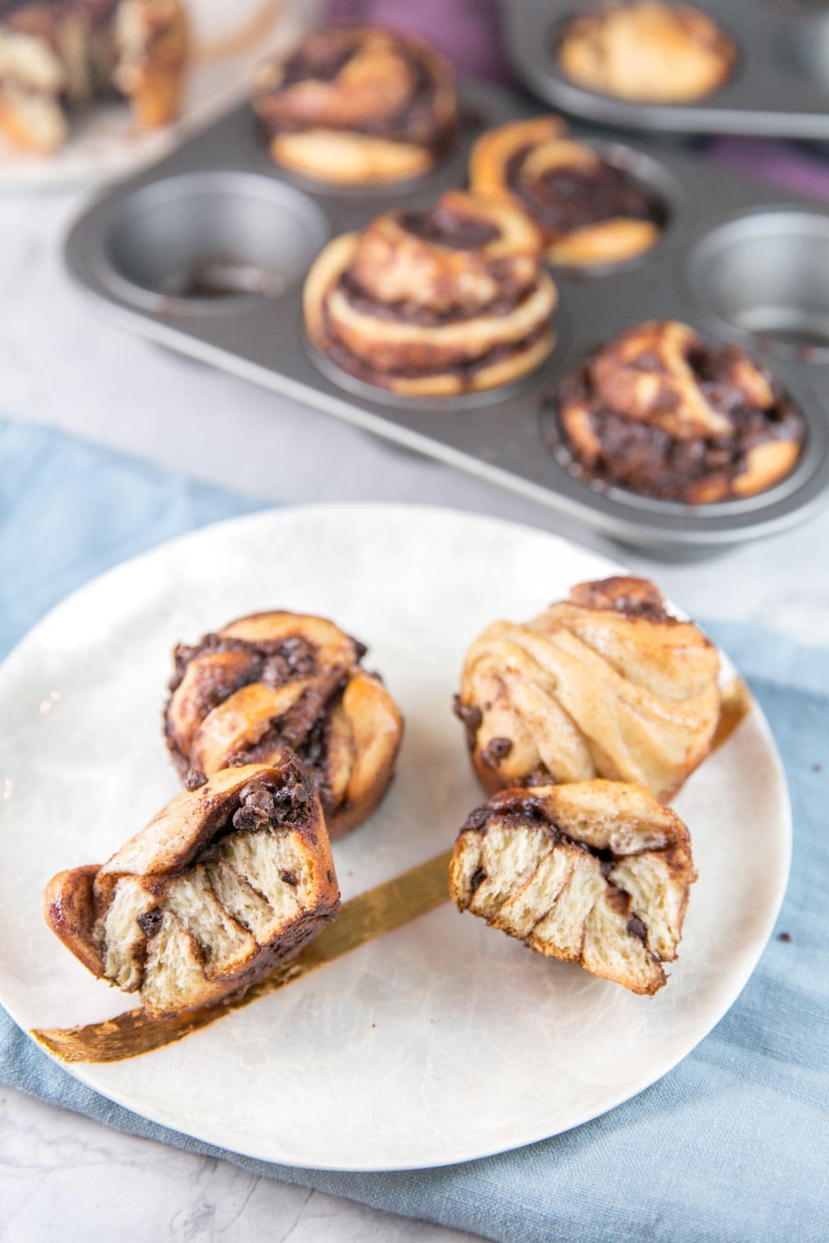 a chocolate babka muffin pulled open to show the layers of chocolate baked into the twisted dough