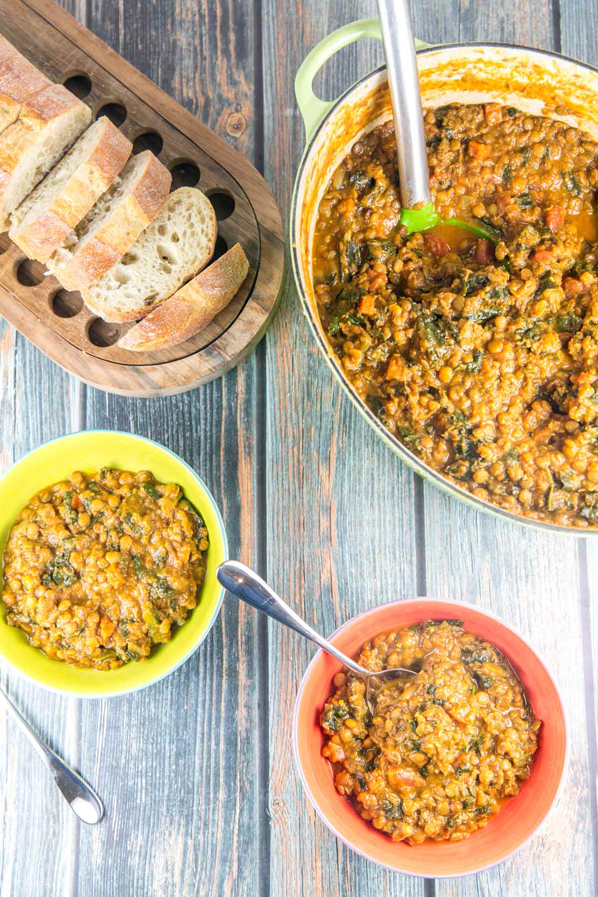 dutch oven full of curried lentil soup with two bowlfuls and sliced bread