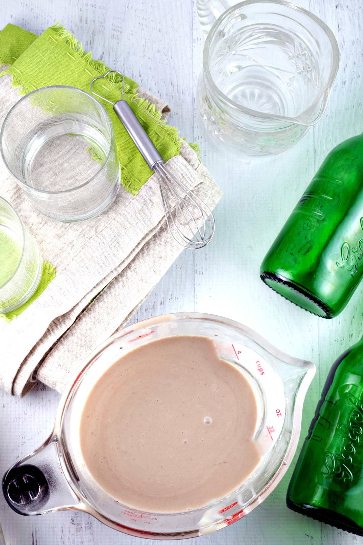batch of irish cream next to green glass bottles and empty rocks glasses