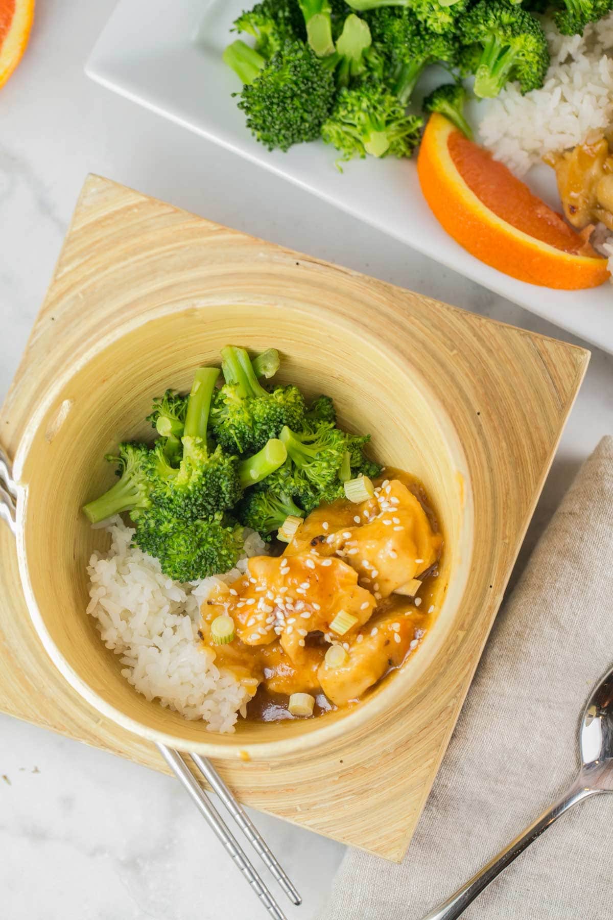 orange chicken, rice, and steamed broccoli in a wooden bowl