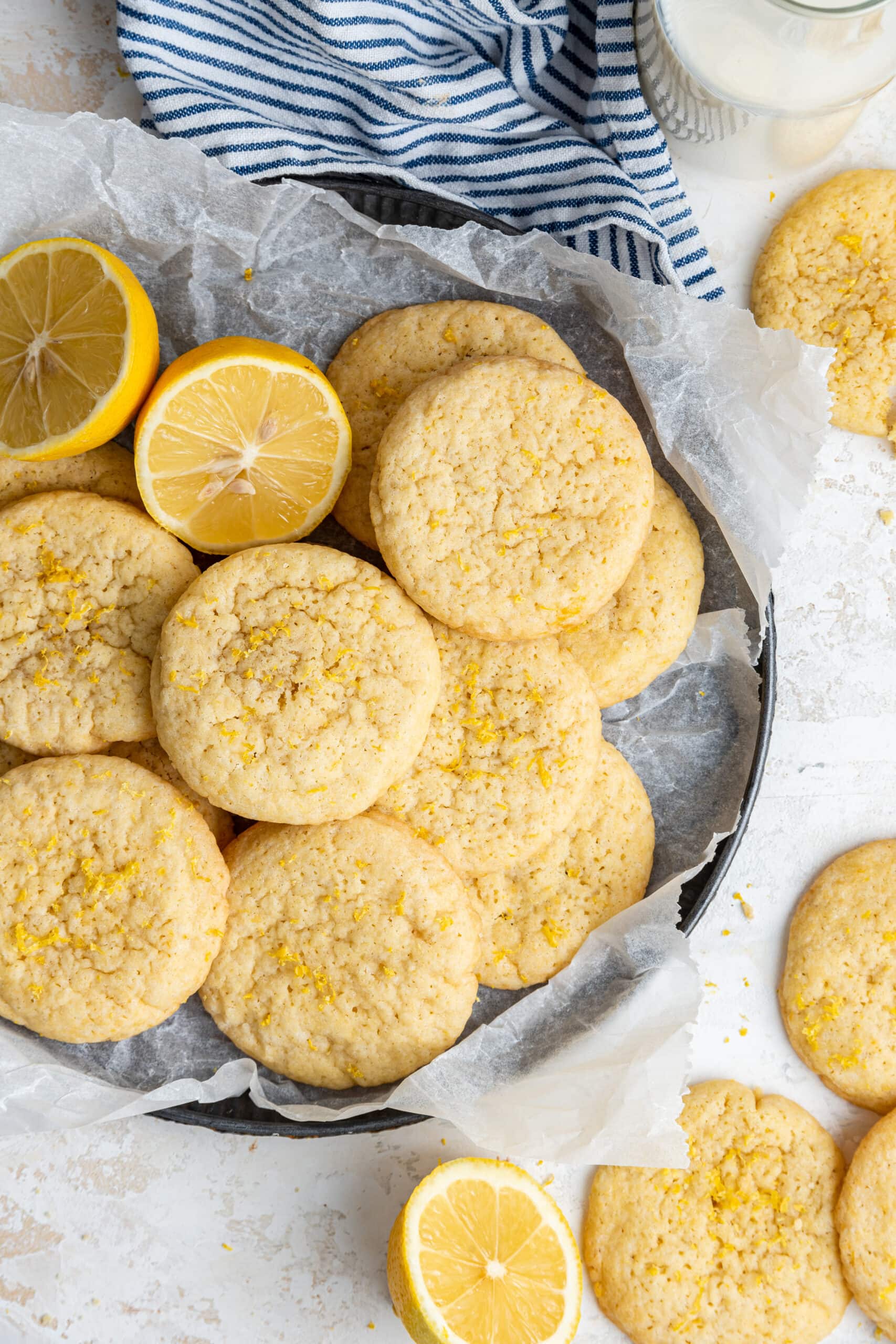 a batch of cookies on parchment paper next to lemon halves