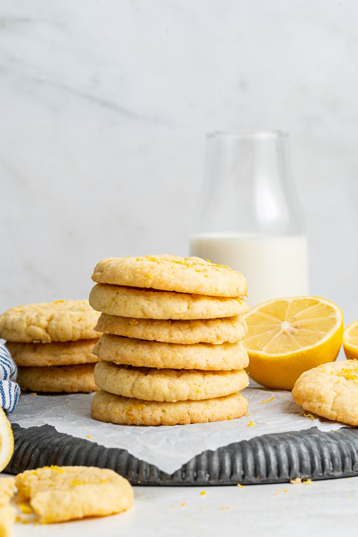 vertical stack cookies next to lemon halves and a jug of milk