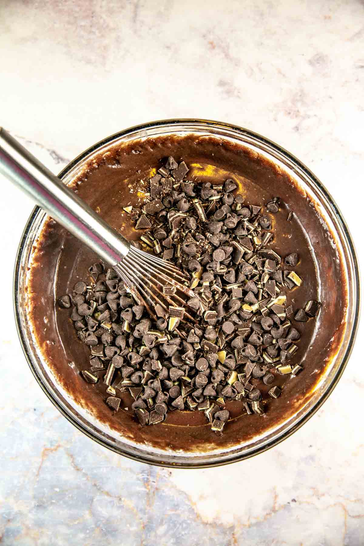 Chocolate being mixed into the chocolate cake batter in a glass mixing bowl. 