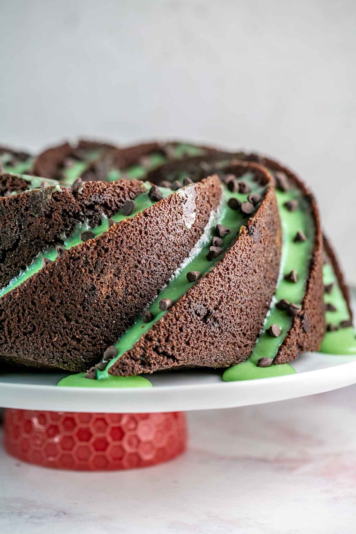 Side view of chocolate bundt cake with green frosting and chocolate chips on top. 