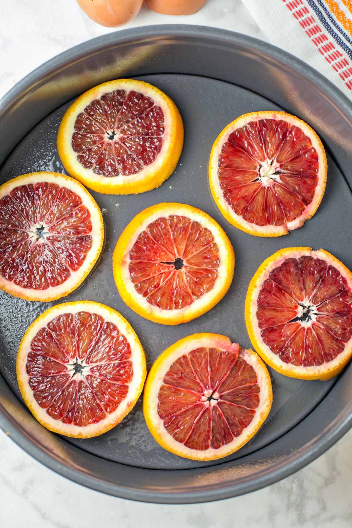 slices of blood oranges arranged in the bottom of a springform pan
