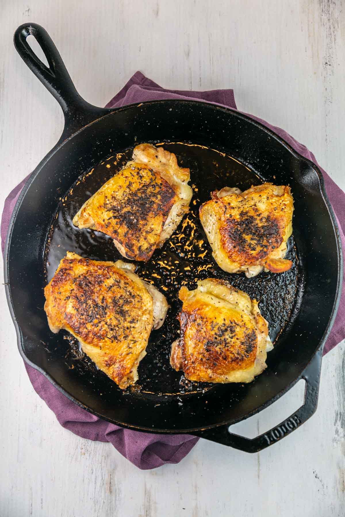 four chicken breasts with seared crispy skin in a cast iron skillet