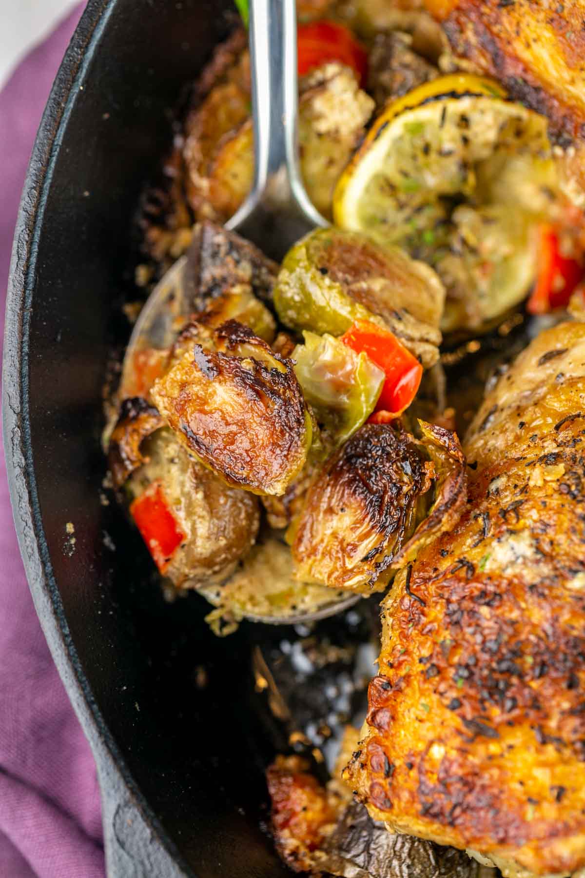 a serving spoon holding up charred brussels sprouts in a tahini sauce