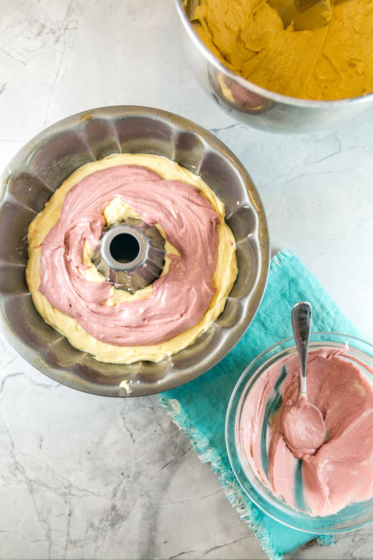 bundt cake pan filled with lemon batter and a layer of pink strawberry lemonade flavored batter