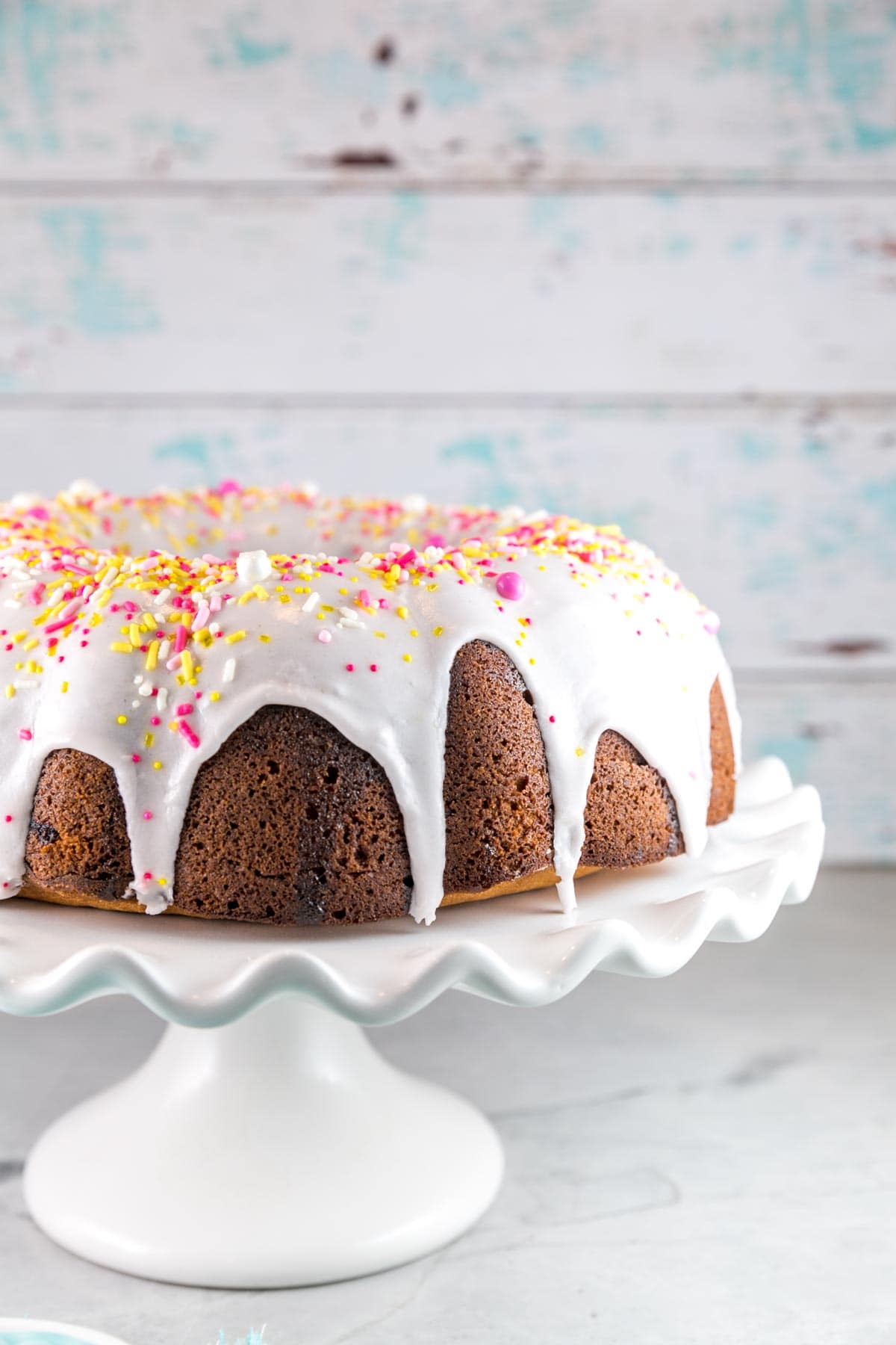 pink lemonade bundt cake covered in sprinkles on a cake serving plate