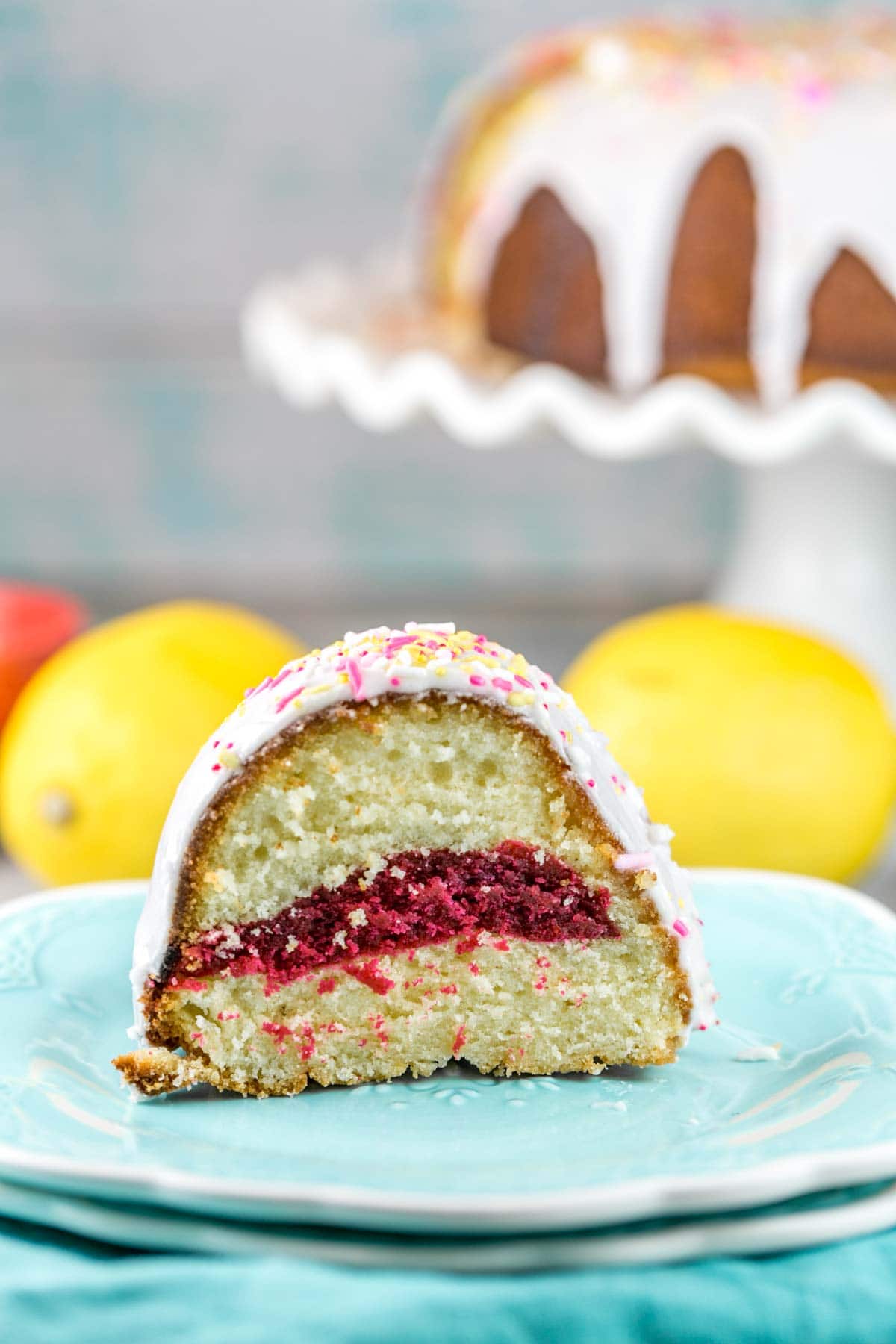 a slice of lemon bundt cake with a bright pink center on a blue dessert plate