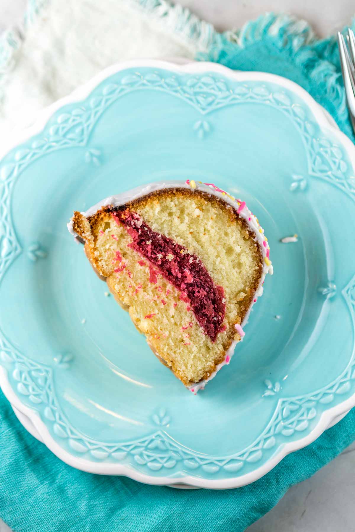 a slice of pink lemonade bundt cake showing a thick pink stripe running through the cake and the fine tender lemon cake crumb