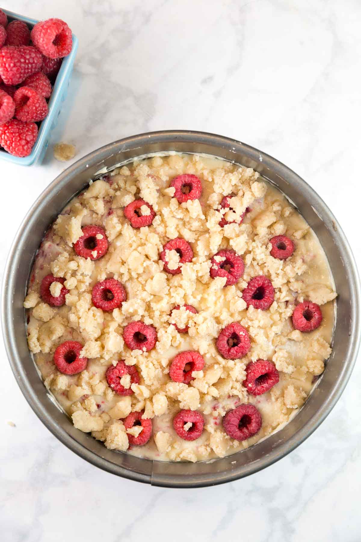 unbaked raspberry crumb cake covered in a butter crumble topping