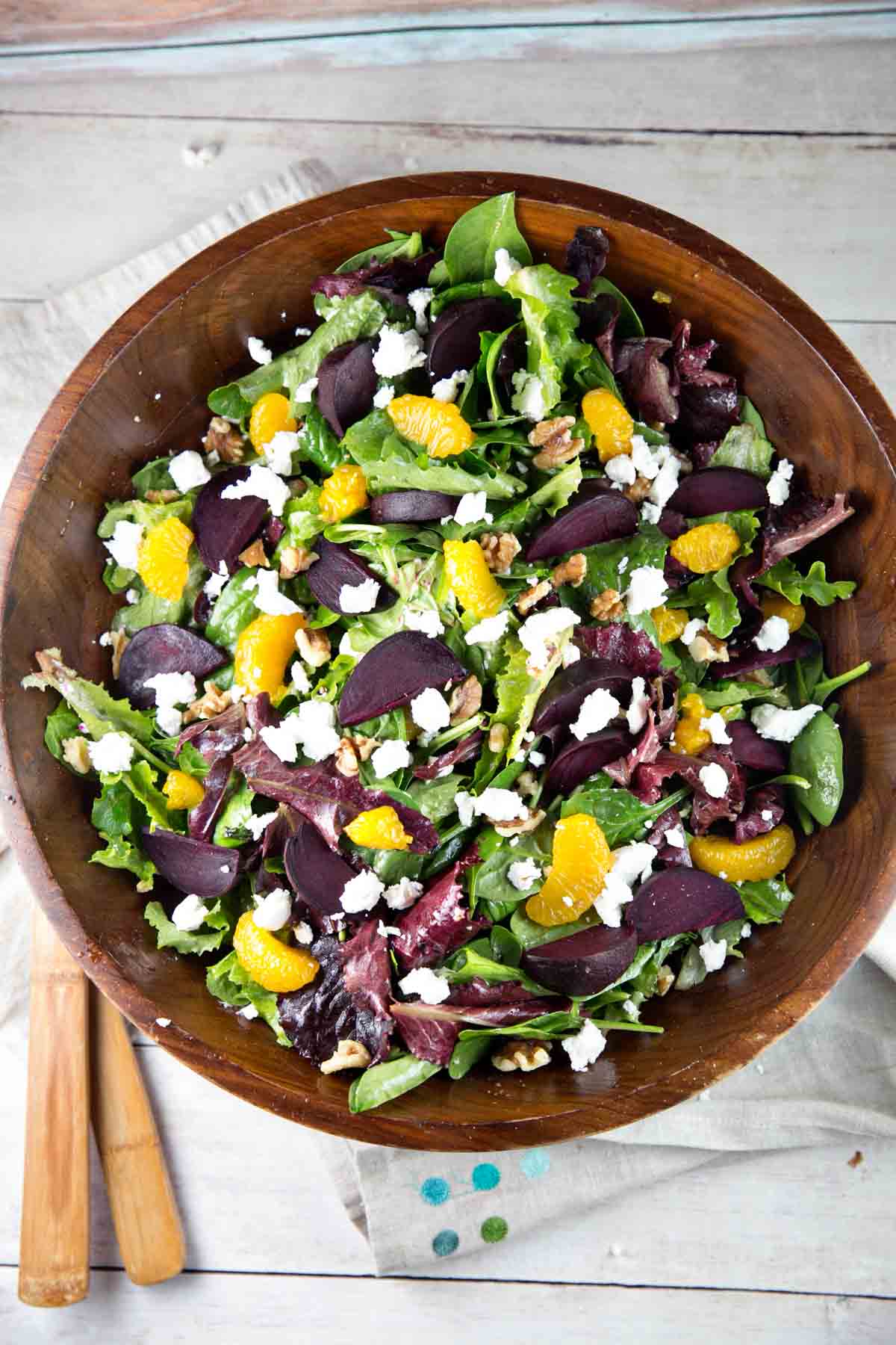 overhead view of a wooden salad bowl filled with roasted beet salad with mandarin oranges and goat cheese