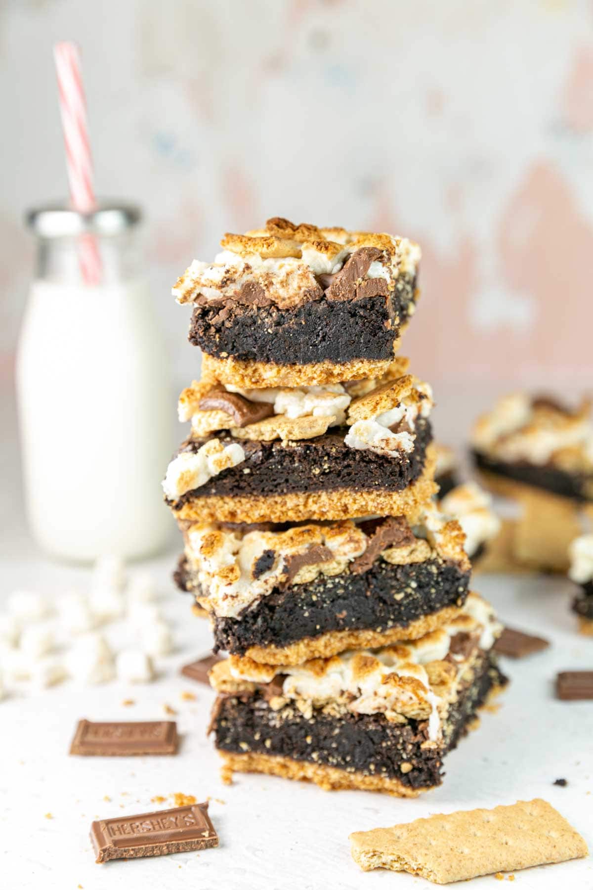 four s'mores brownies stacked in a pile with a milk glass in the background