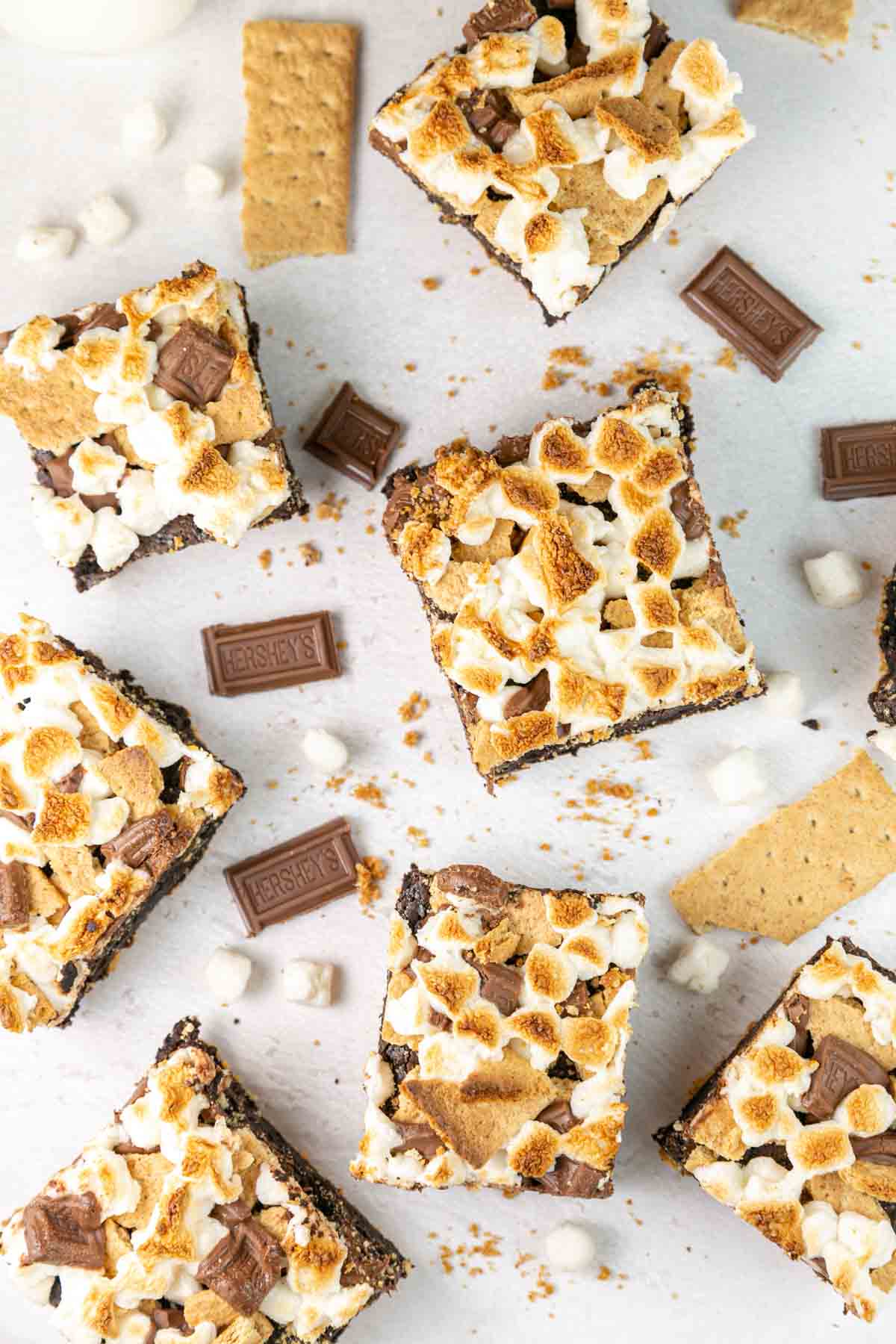 brownies covered in toasted marshmallow with chocolate and graham cracker pieces scattered nearby