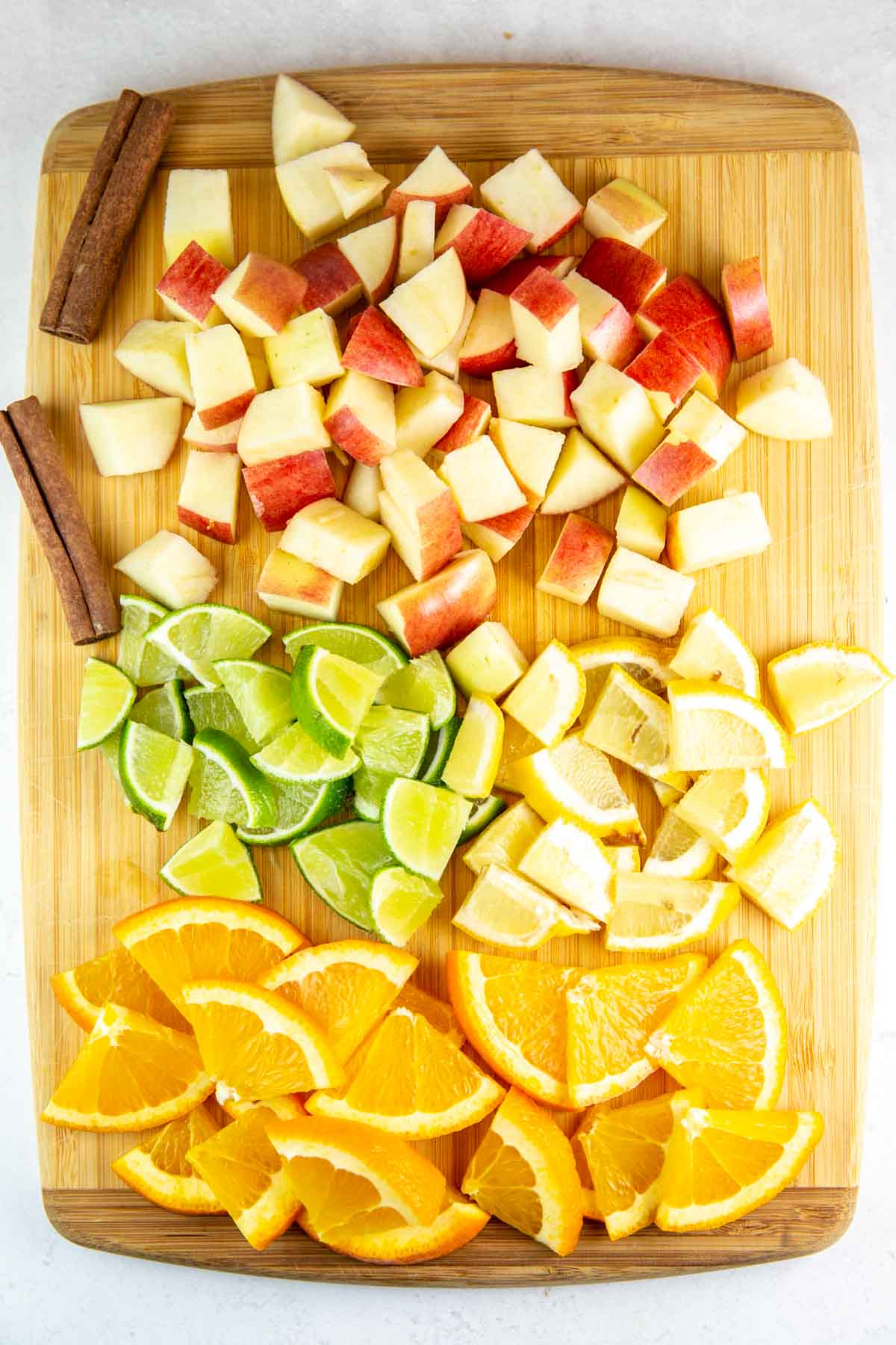 cutting board with chopped apples, limes, lemons, and oranges