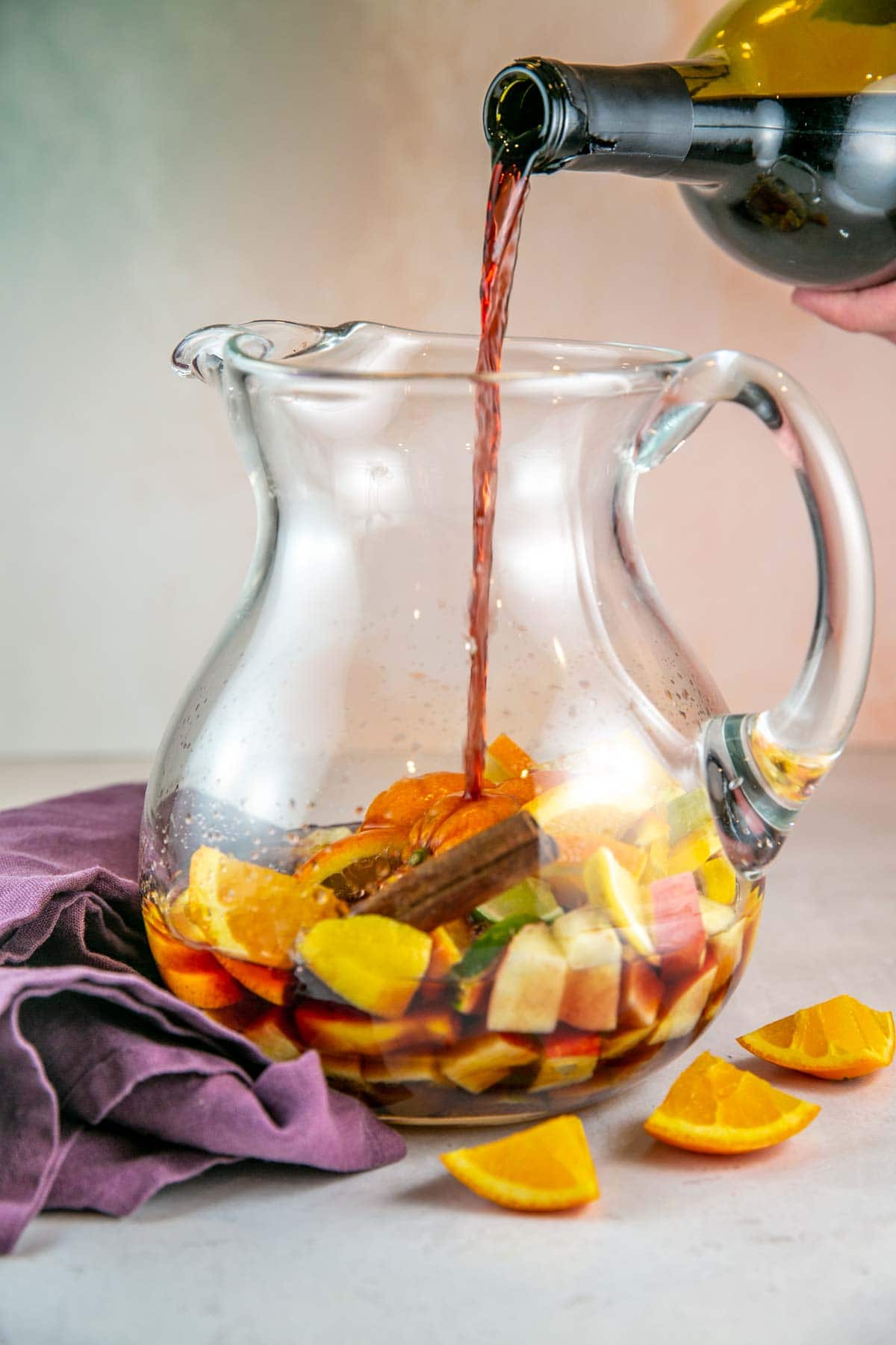 pouring wine into a glass pitcher to make sangria