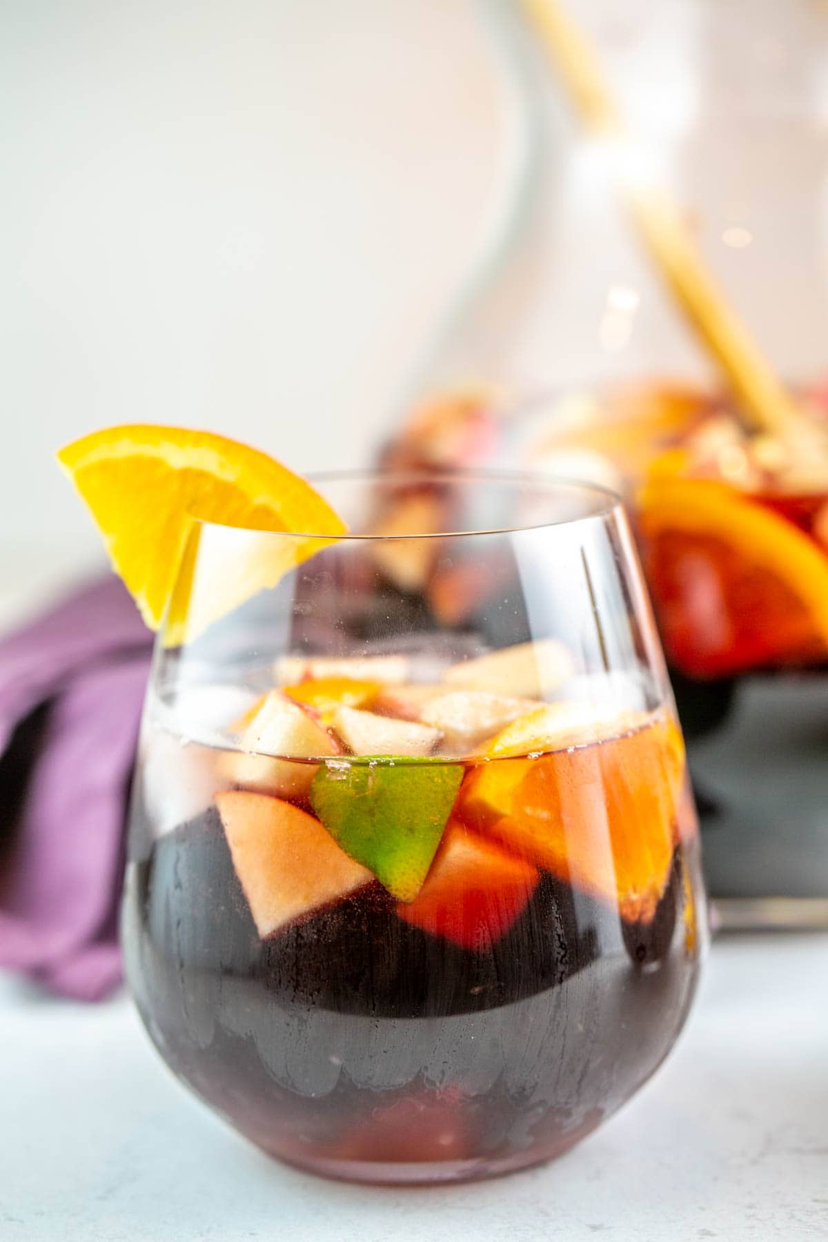 stemless wine glass filled with sangria with an orange on the rim
