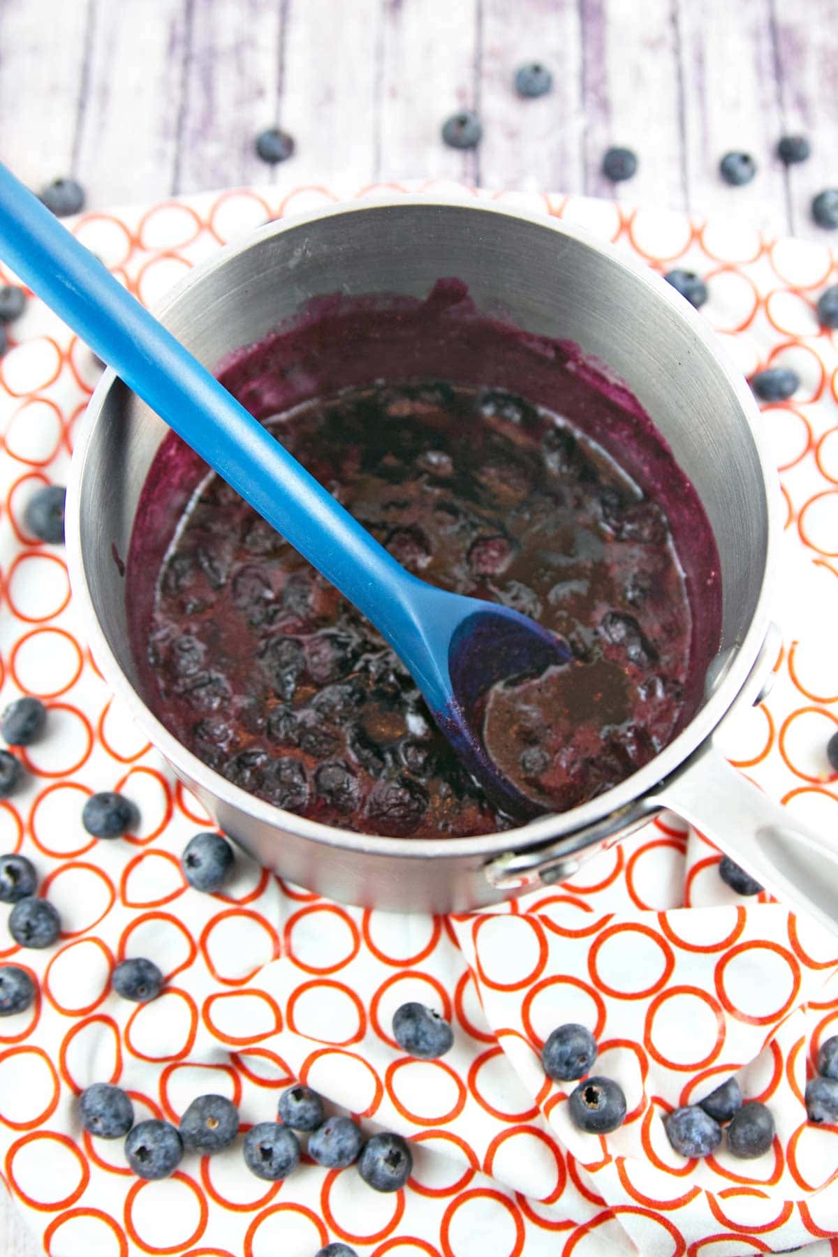 cooking down blueberries in a big pot to make homemade blueberry curd