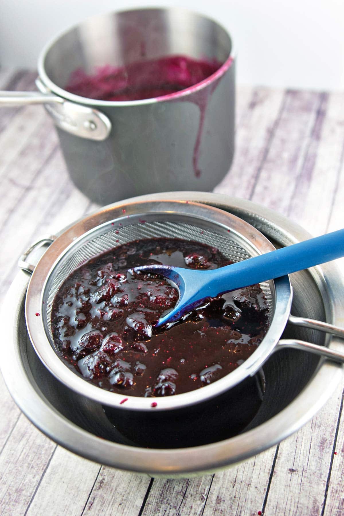 straining cooked blueberries through a fine mesh sieve