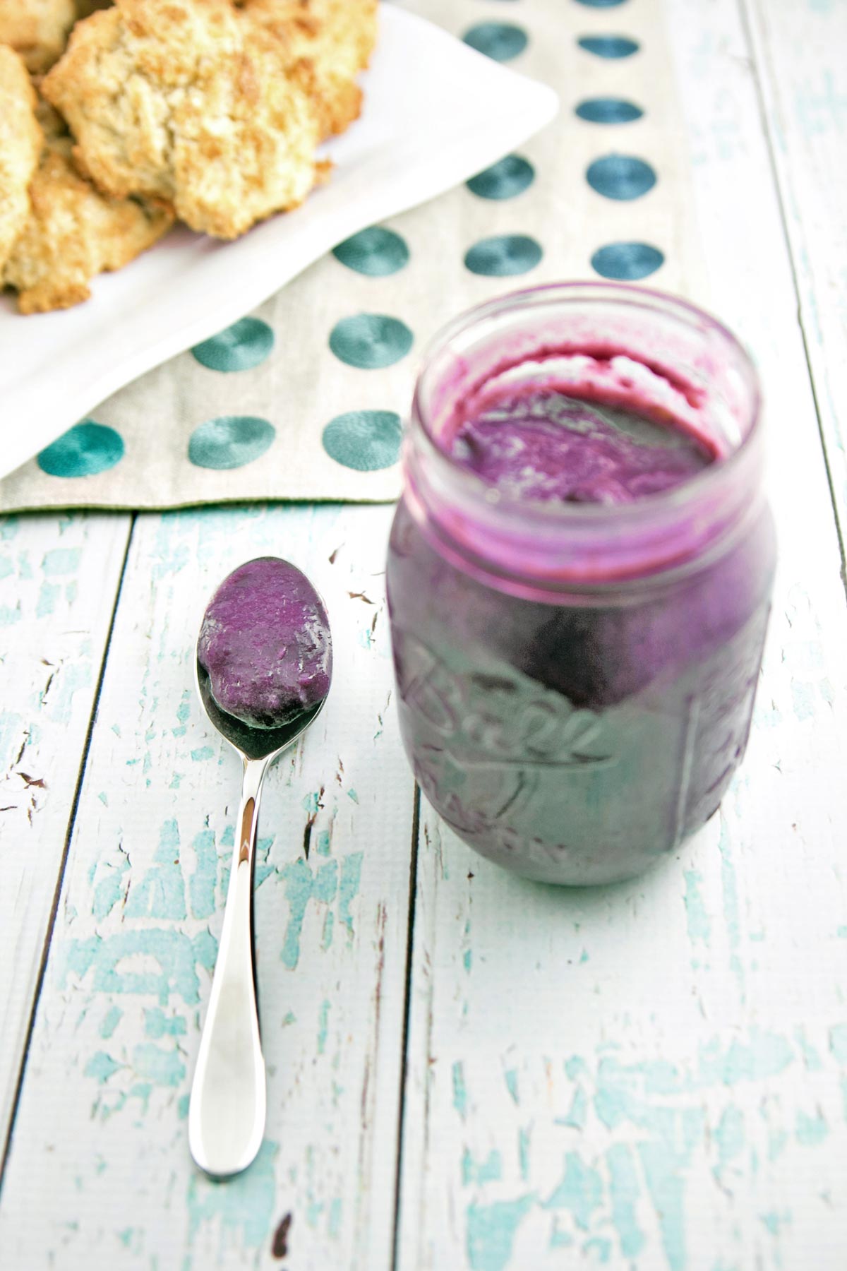 mason jar filled with blueberry curd next to a heaping spoonful