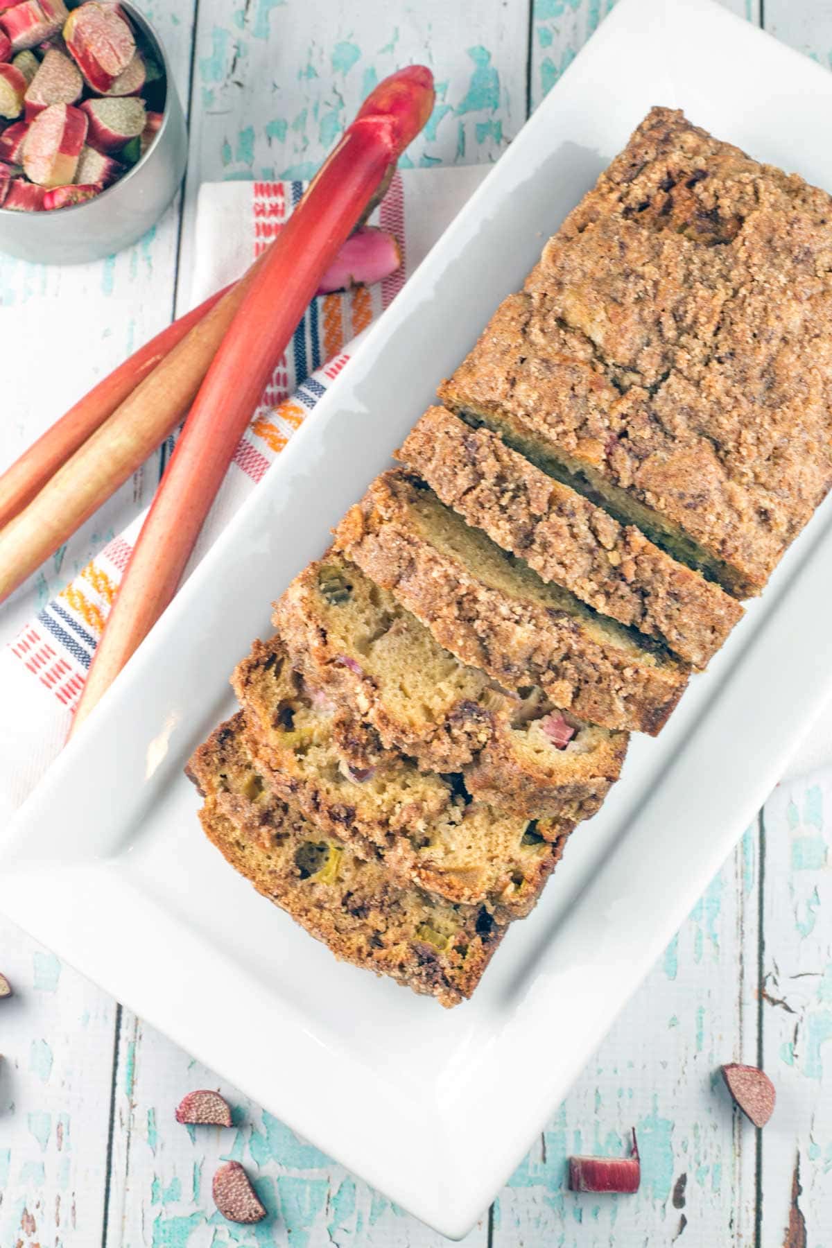 loaf of rhubarb quick bread on a white rectangular serving plate