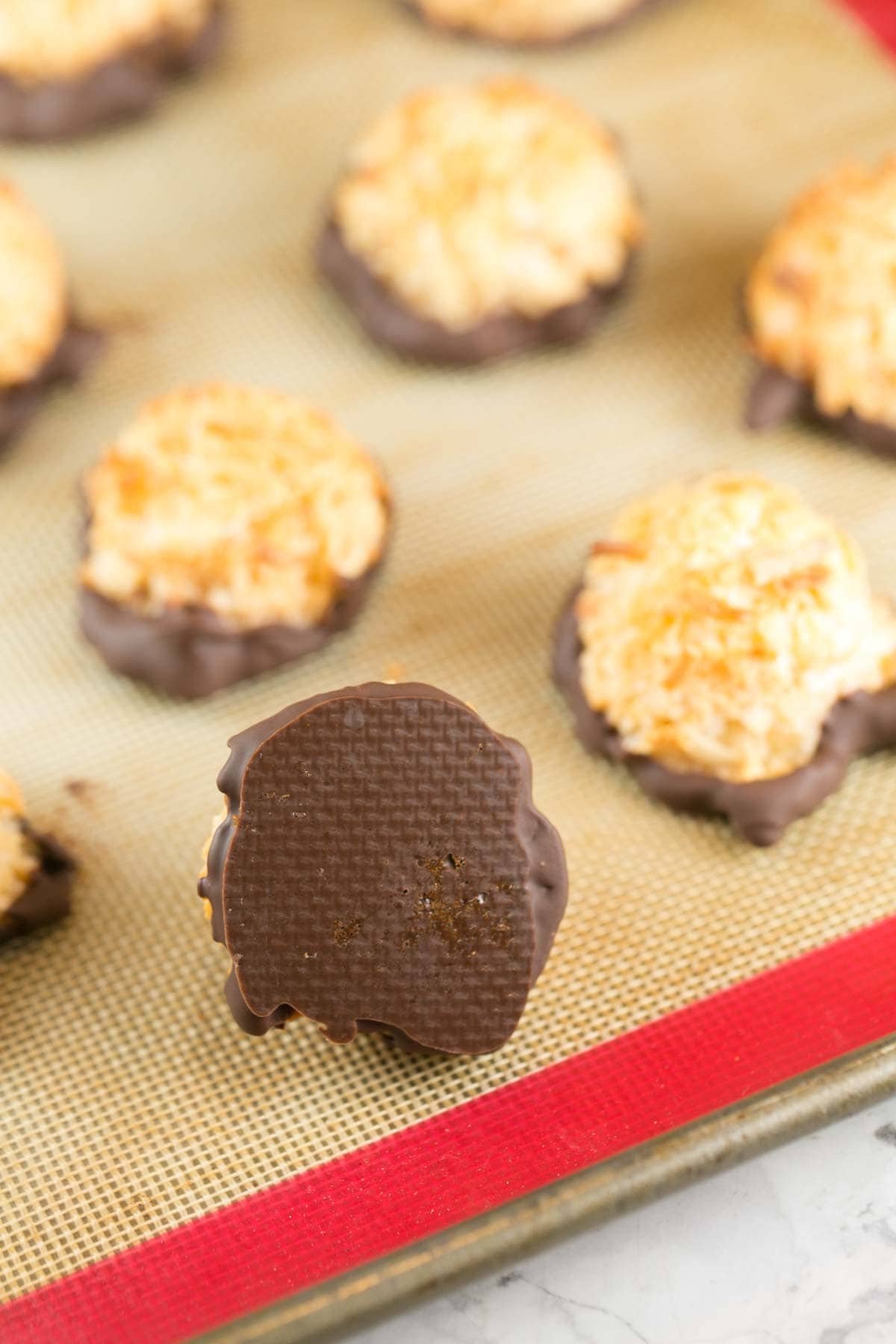an upside-down chocolate dipped coconut macaroon showing how easily the melted chocolate comes off the baking sheet