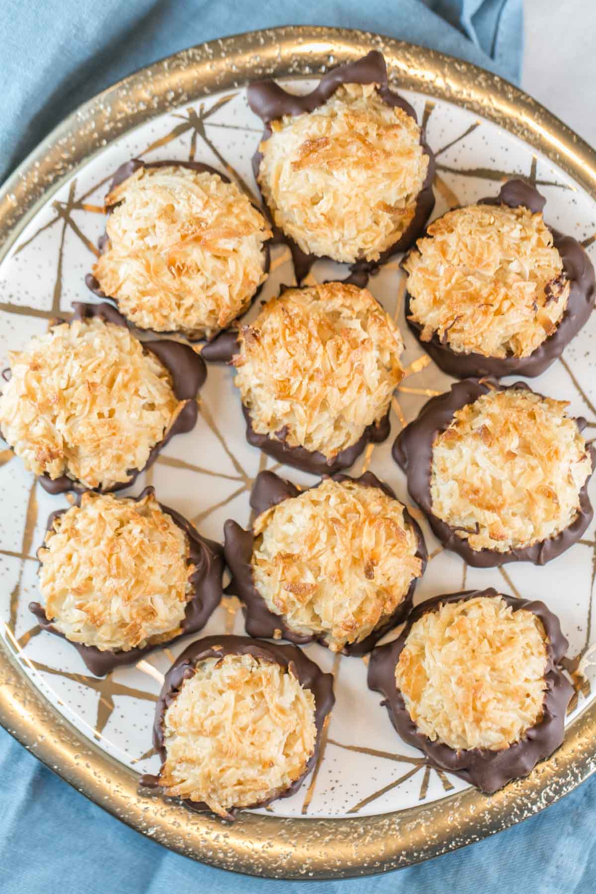 a decorative gold plate filled with chocolate dipped coconut macaroons