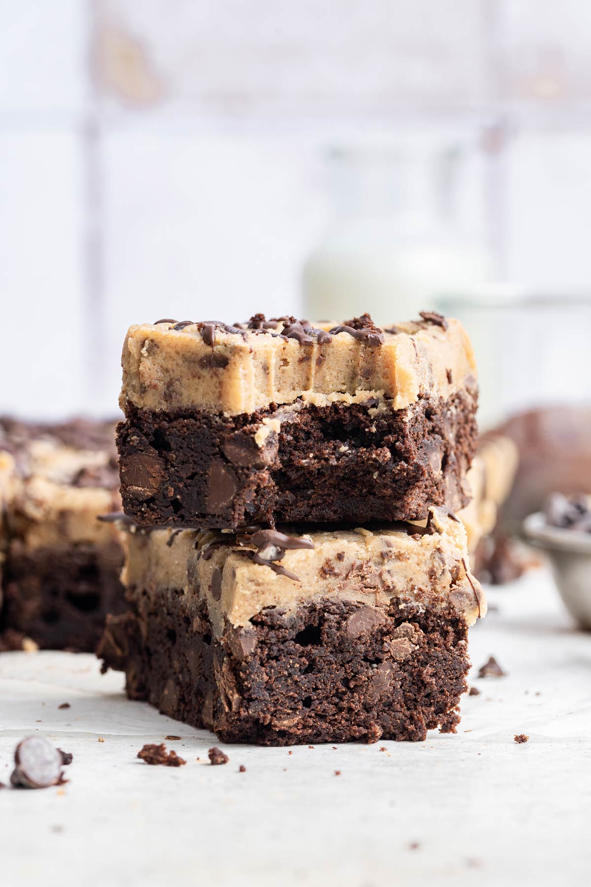 stack of two brownies with cooking dough frosting with a bite taken out of one brownie