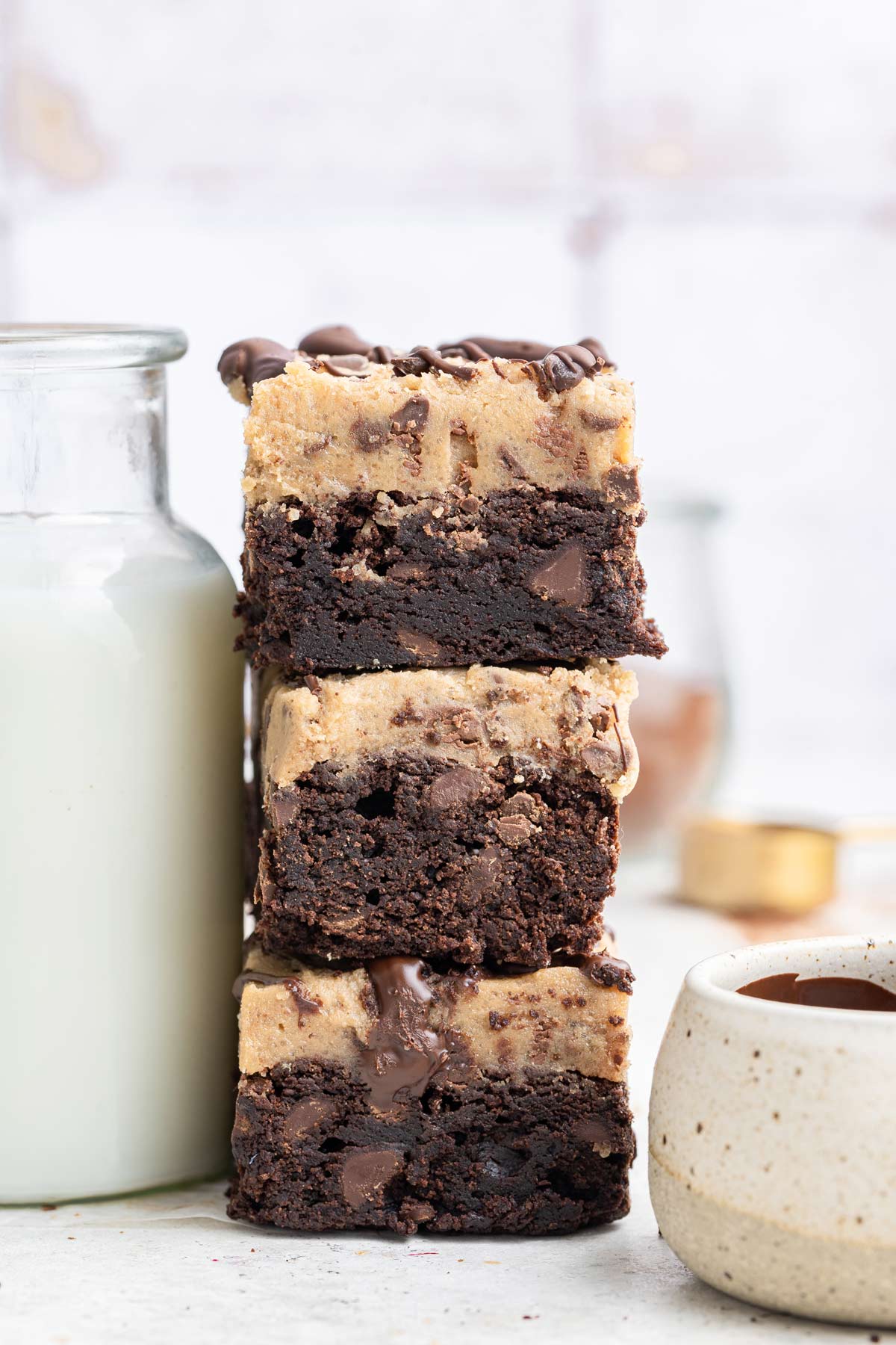 cookie dough brownies stacked next to a glass jar of milk