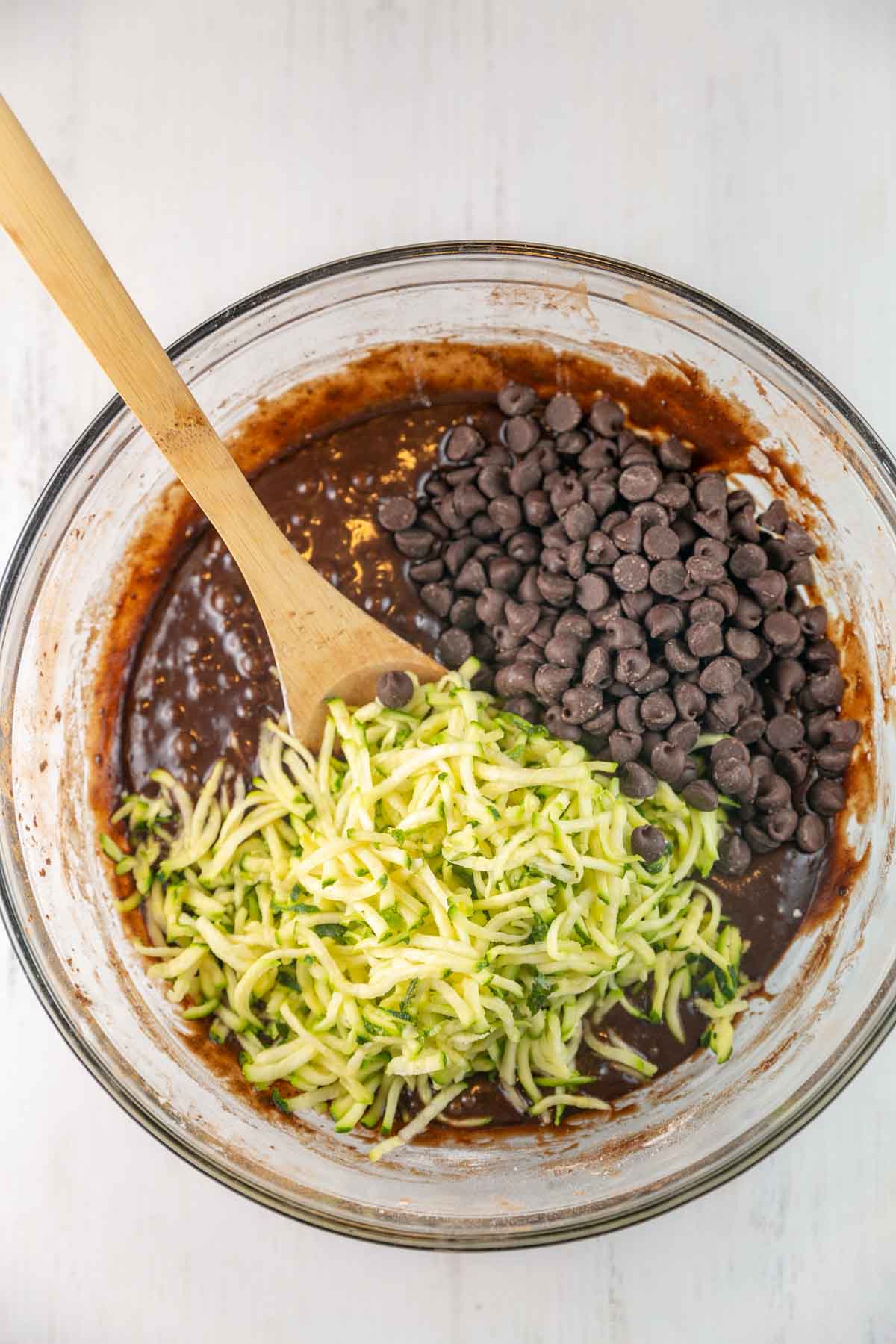 a bowl of brownie batter with shredded zucchini on top