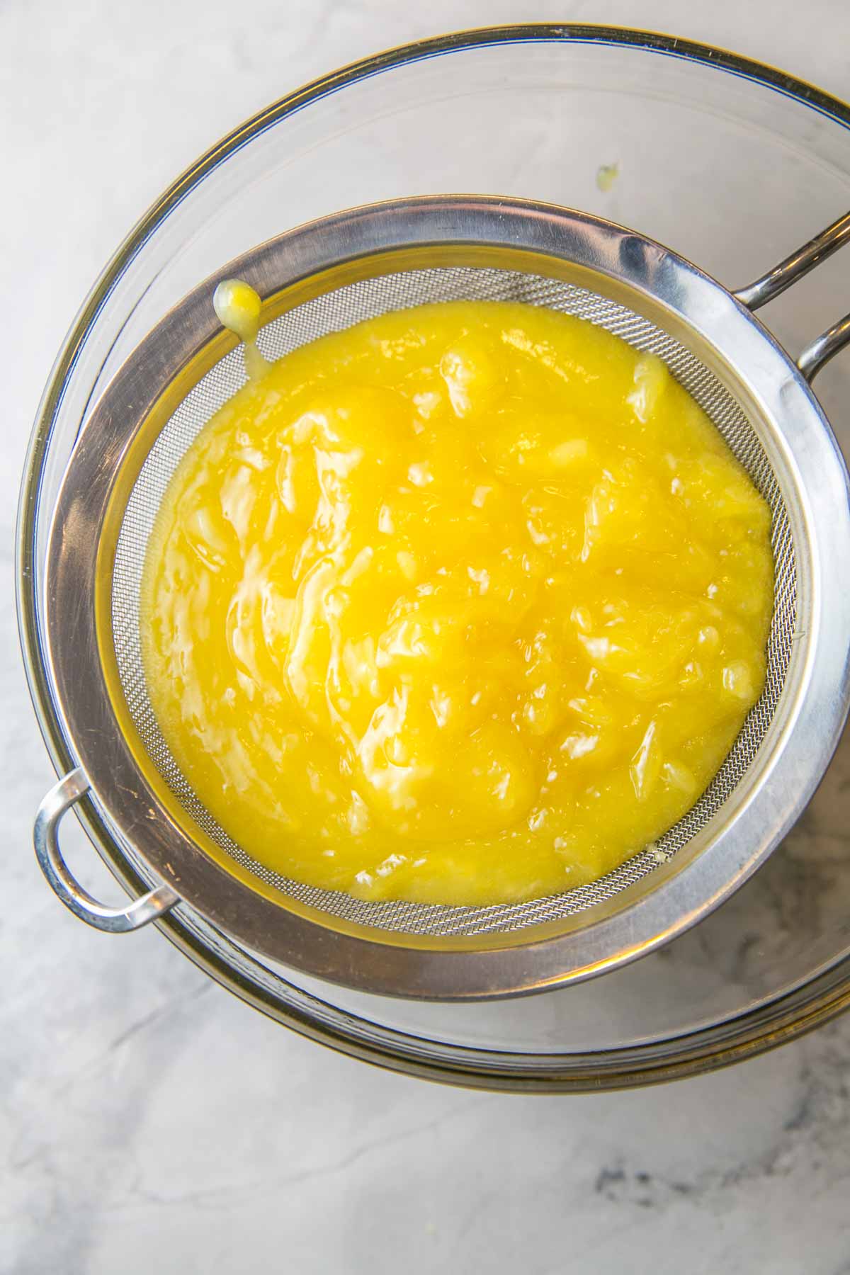 straining freshly made lemon curd in a mesh sieve to remove any clumps