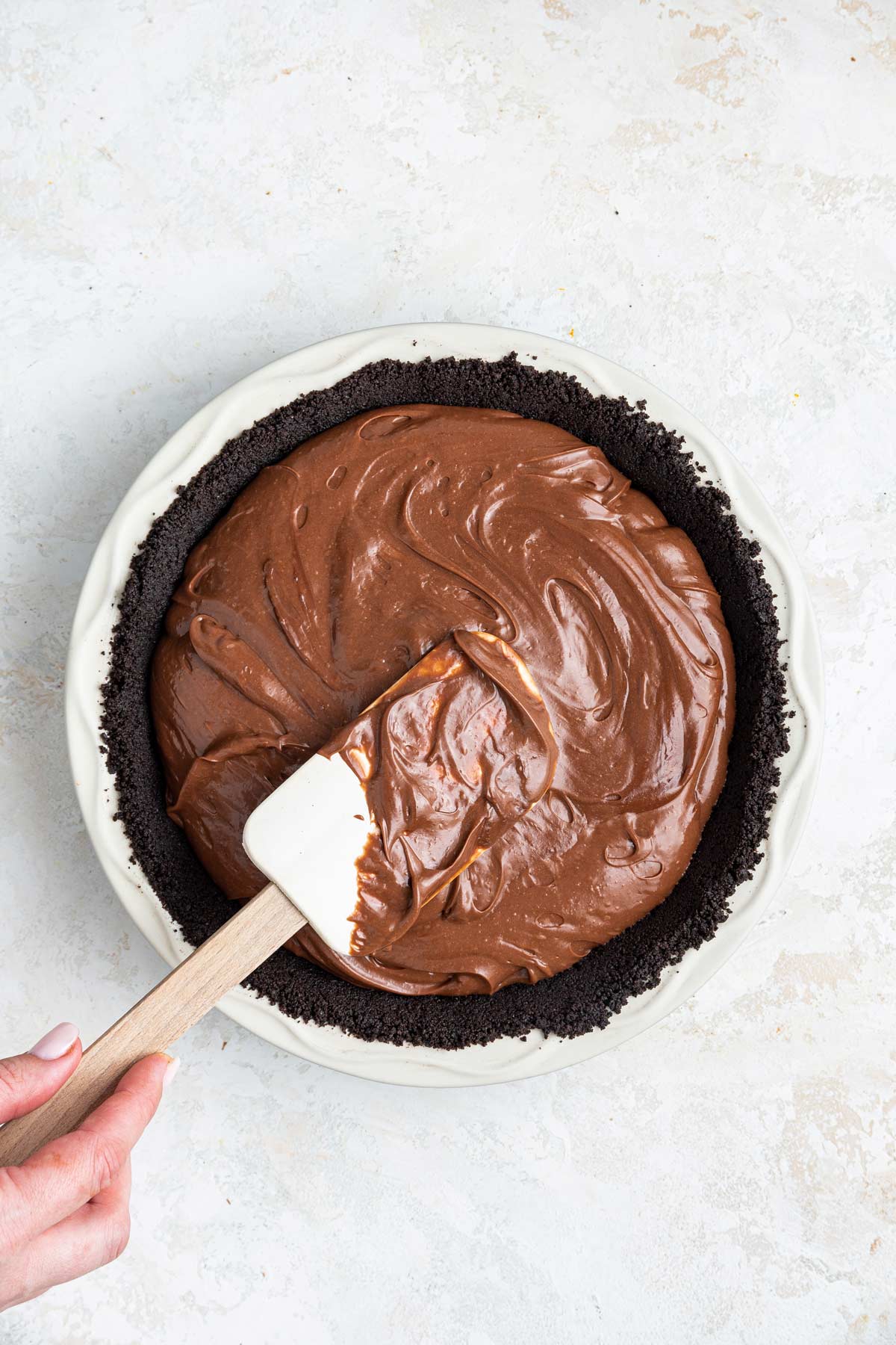 spatula smoothing the nutella filing in an oreo cooking crust