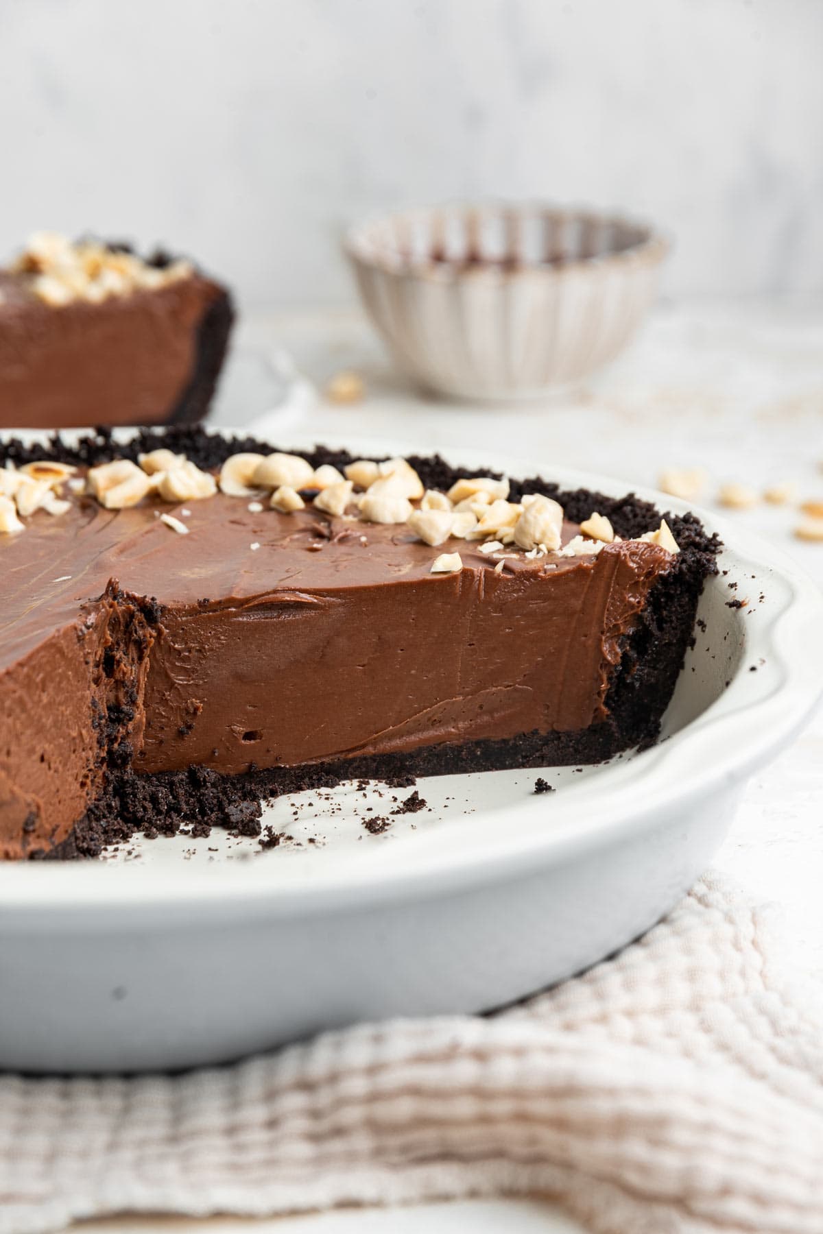 side view of a pie plate with an oreo cookie crust filled with chocolate custard