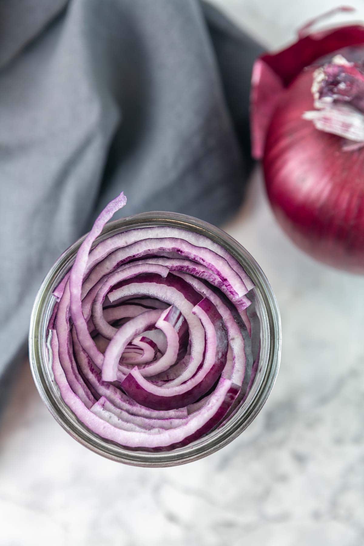 overhead view of a glass jar packed full with sliced red onion