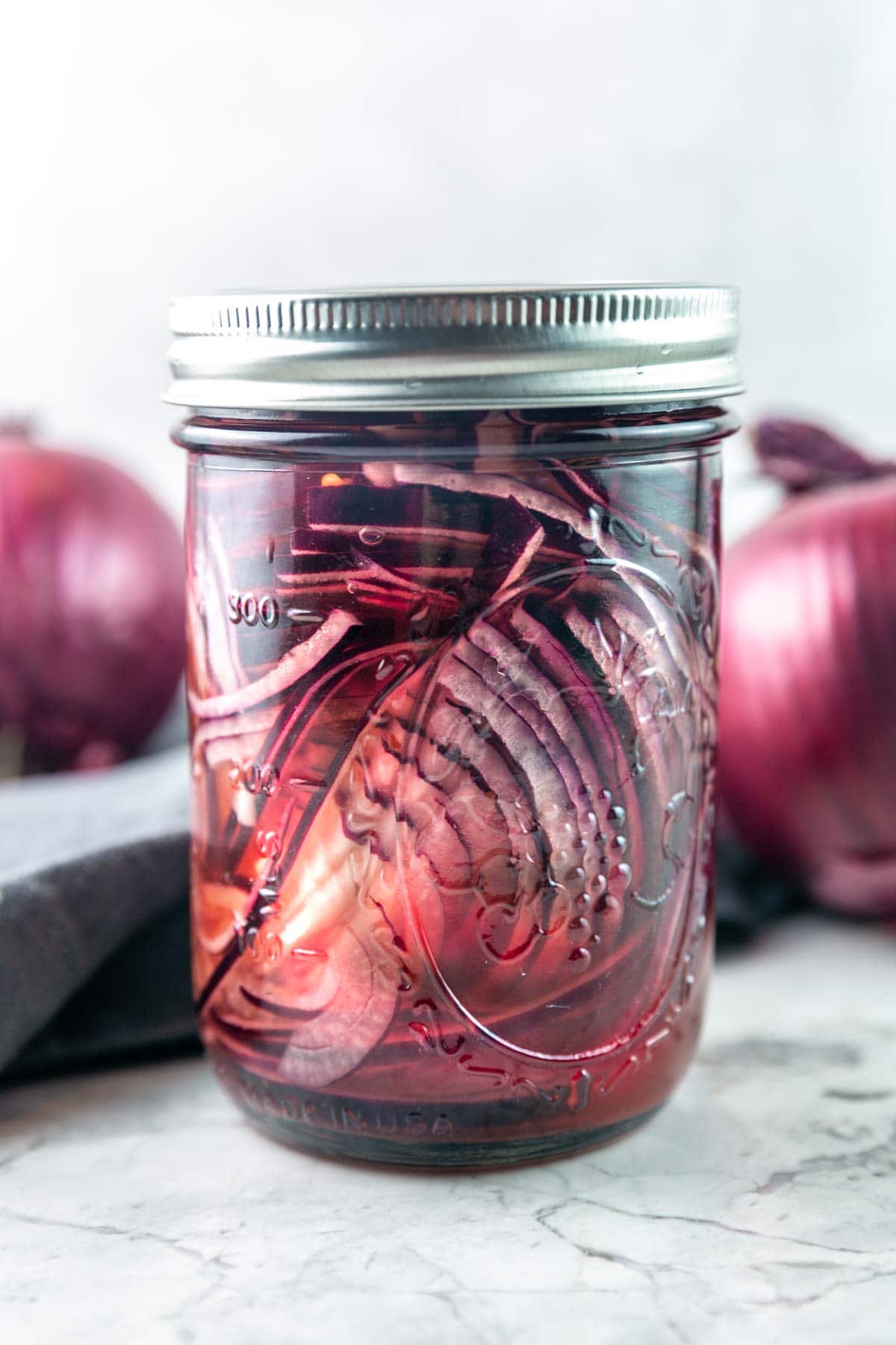 glass mason jar filled with thinly sliced red onions and pickling brine