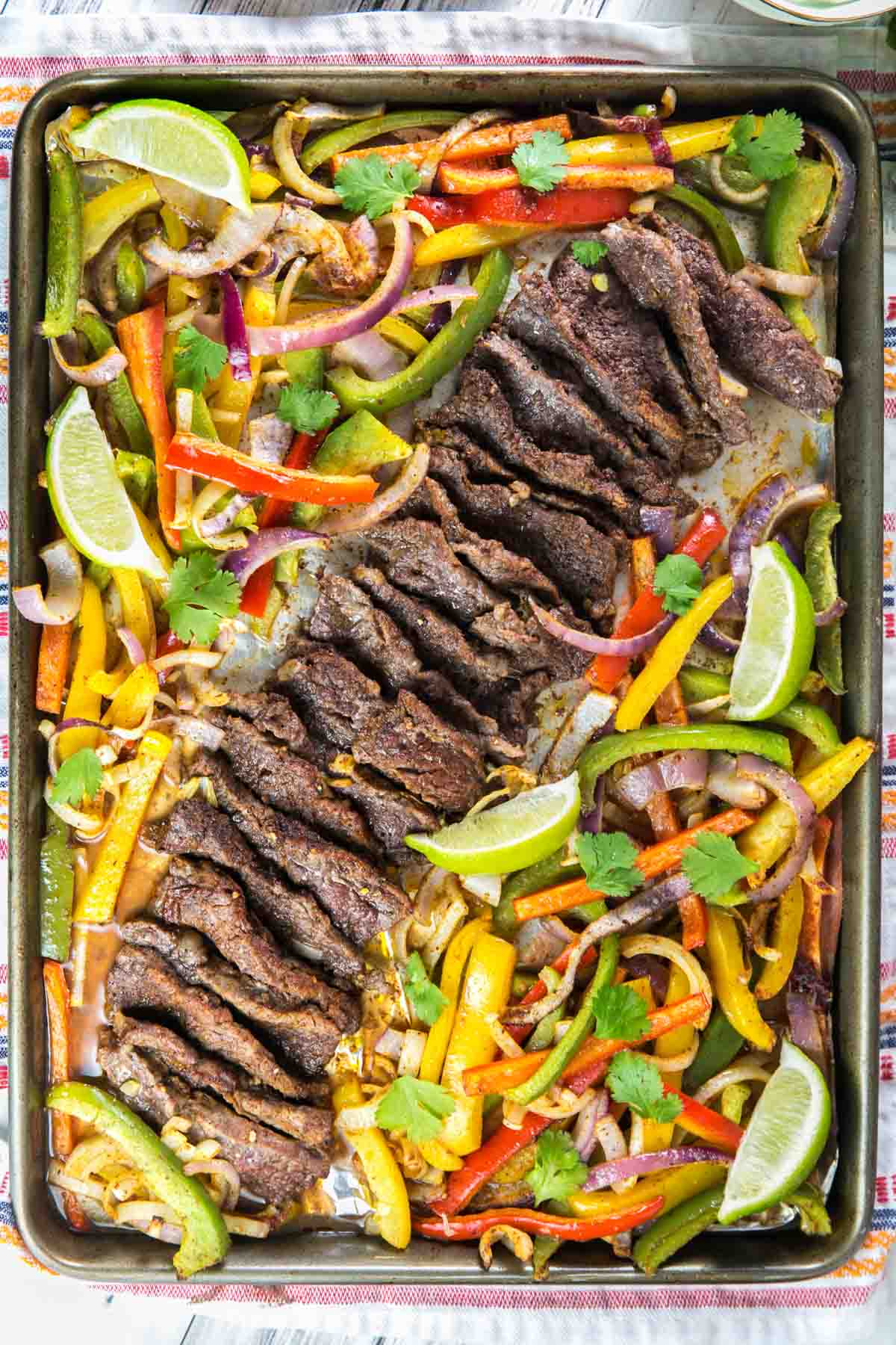 large sheet pan with thinly sliced steak arranged diagonally across the pan