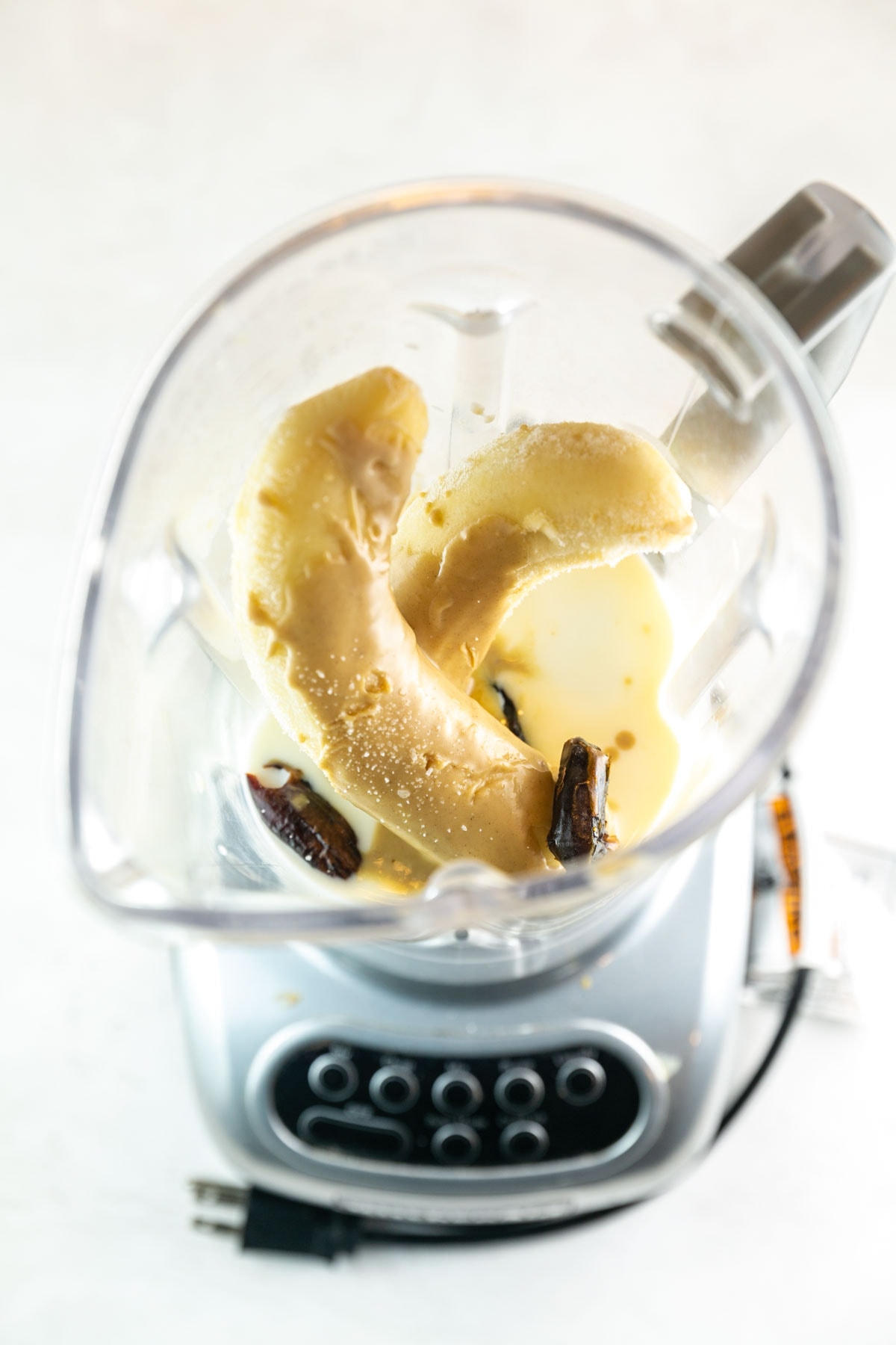 a blender filled with milk, bananas, tahini, and dates