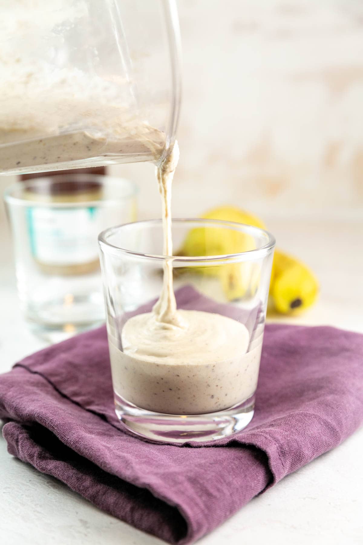 pouring a thick tahini shake from the blender into a glass