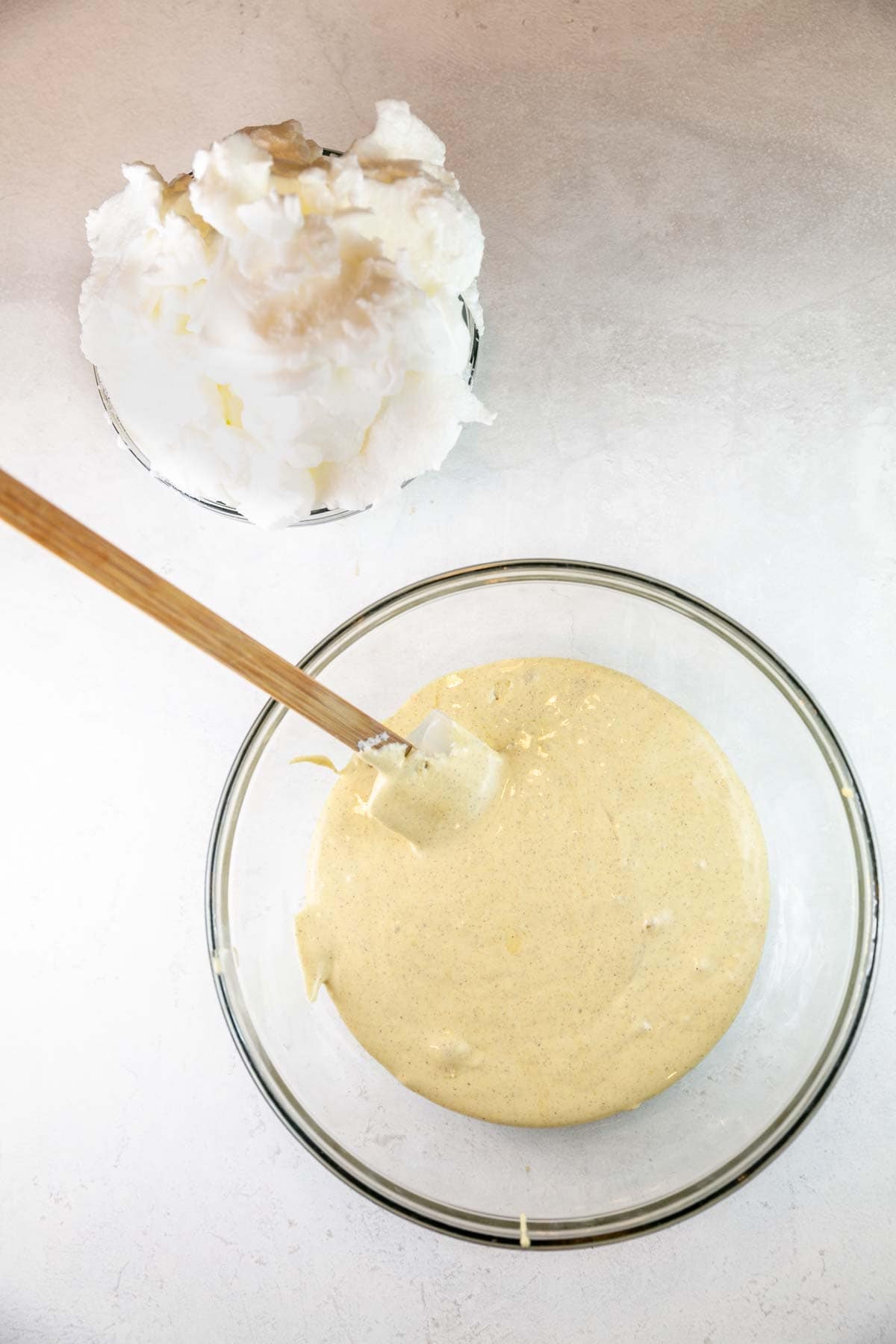 cake batter in mixing bowl next to a pile of whipped egg whites