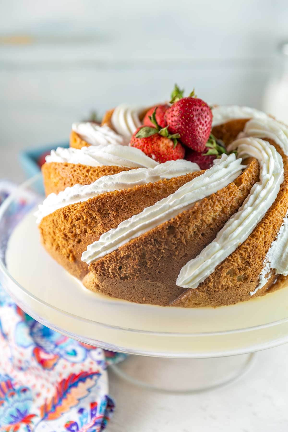 sponge cake baked in a bundt pan soaked in milk and decorated with whipped cream and strawberries