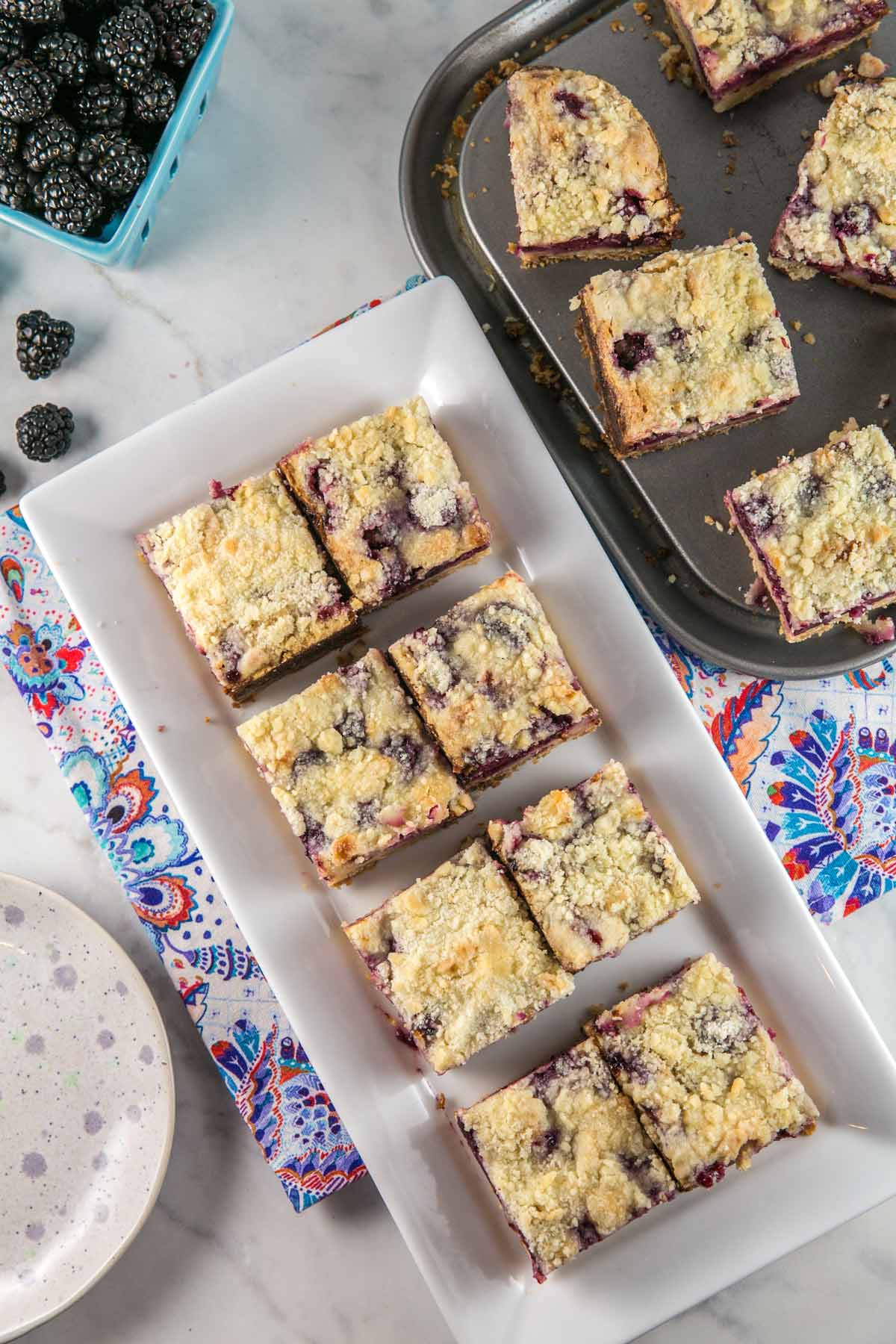 overhead view of blackberry pie bars on a serving plate and in an 8x8 baking pan