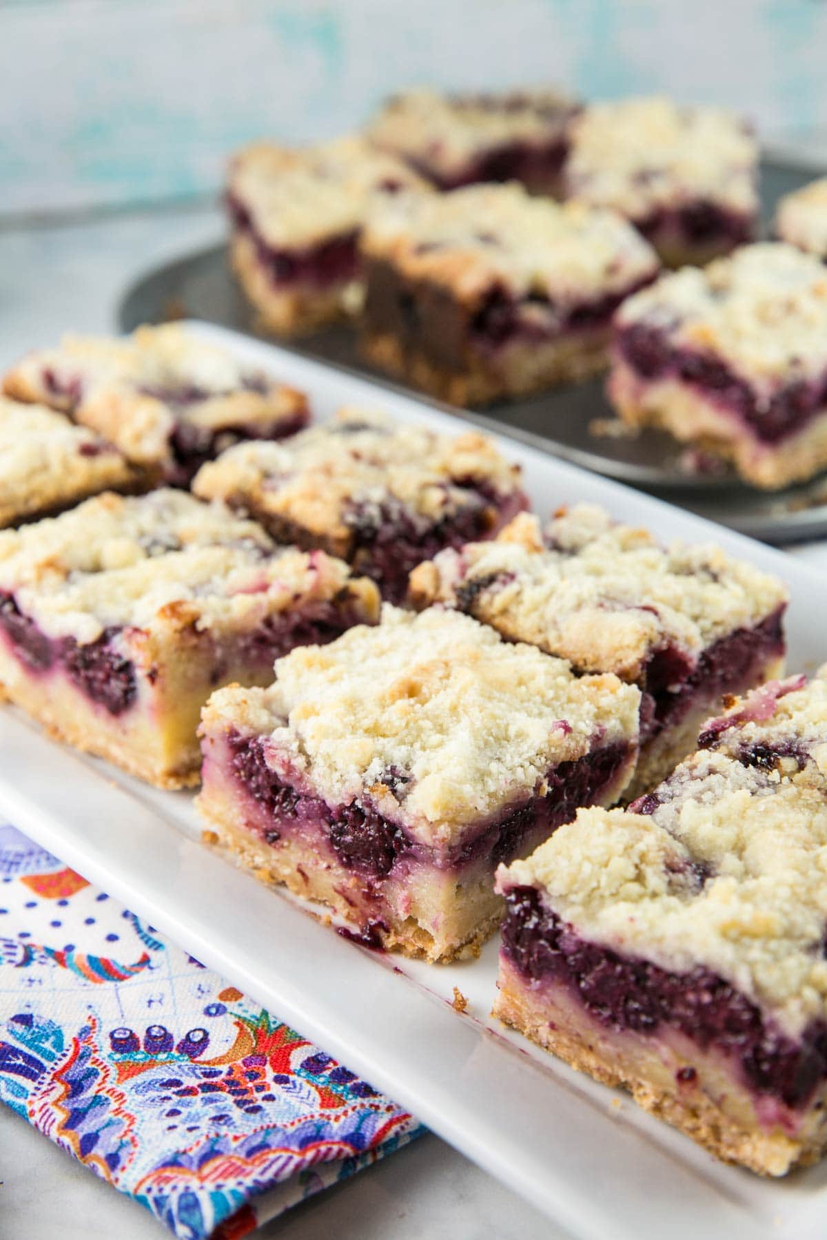 eight blackberry pie bars arranged on a rectangular serving plate