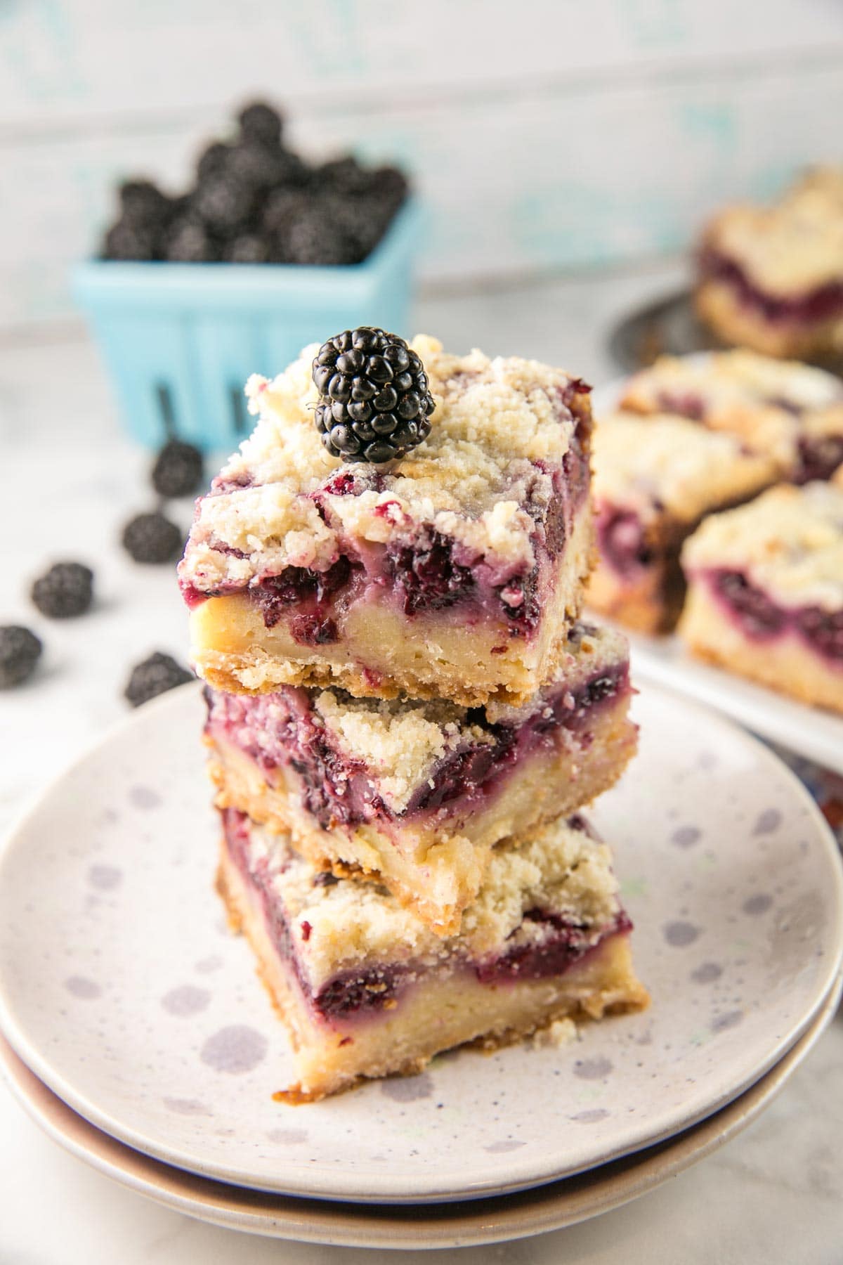three blackberry pie bars stacked vertically on a patterned dessert plate