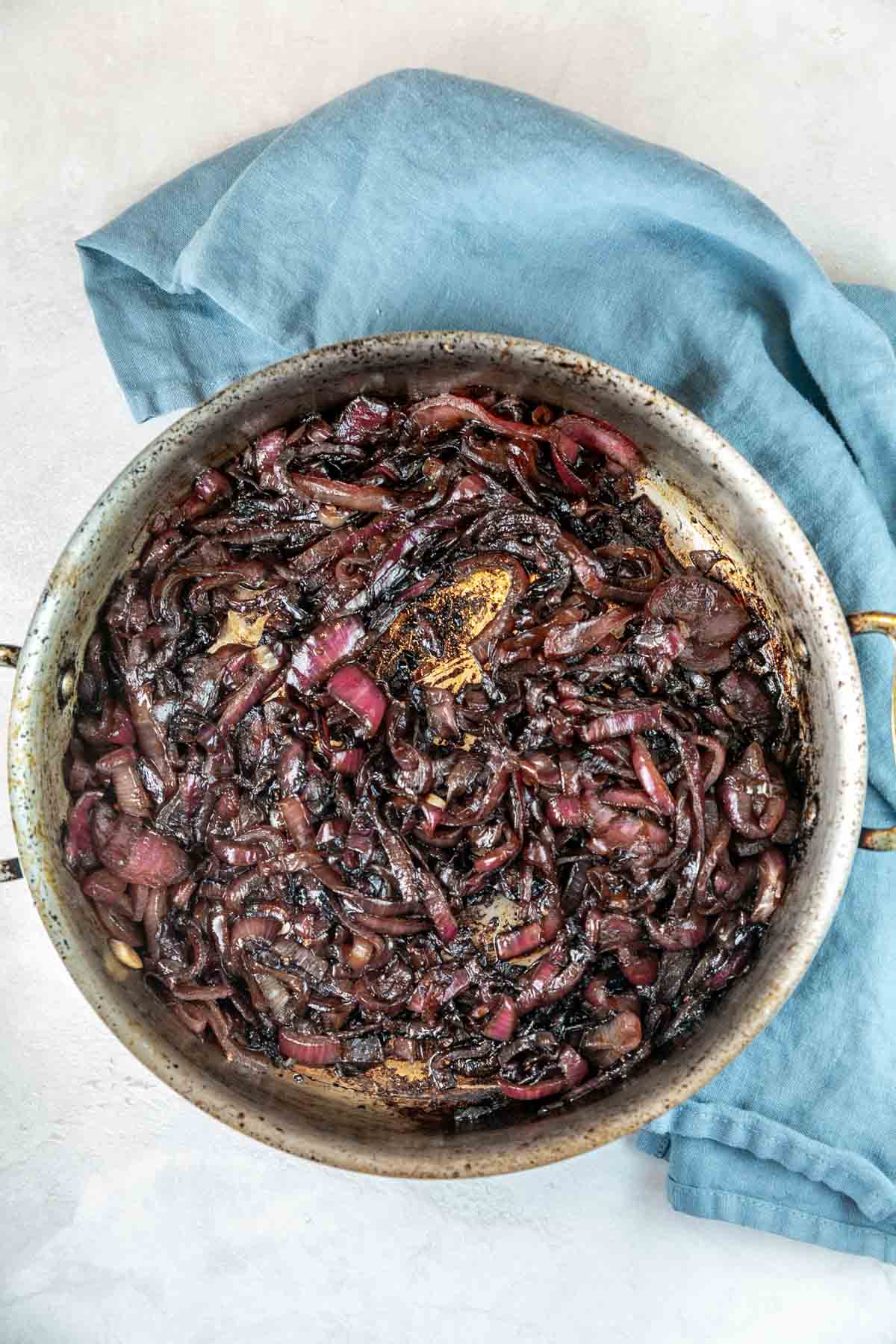 large saute pan filed with caramelized red onions with a balsamic glaze