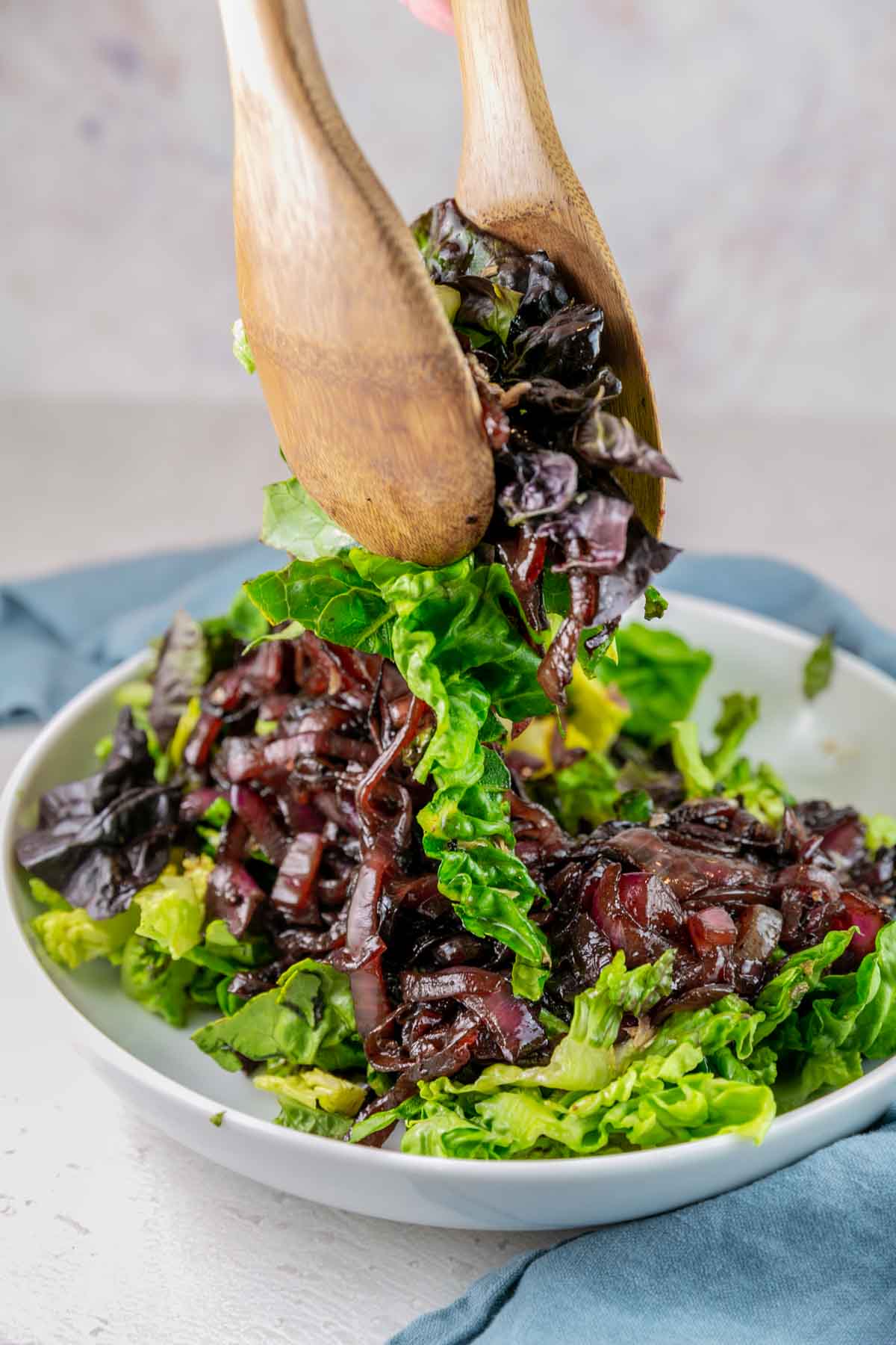 wooden salad tongs mixing butterleaf lettuce and caramelized onions