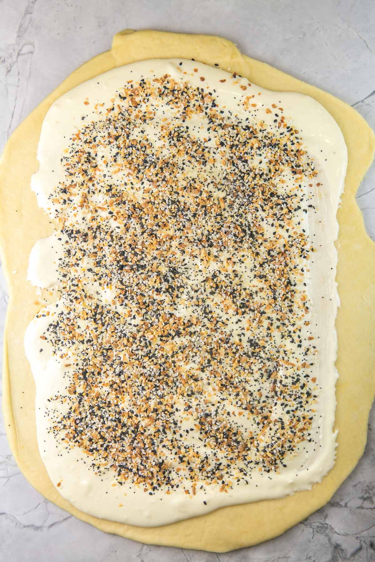rolled out babka dough with a layer of cream cheese and a generous covering of everything bagel seasoning