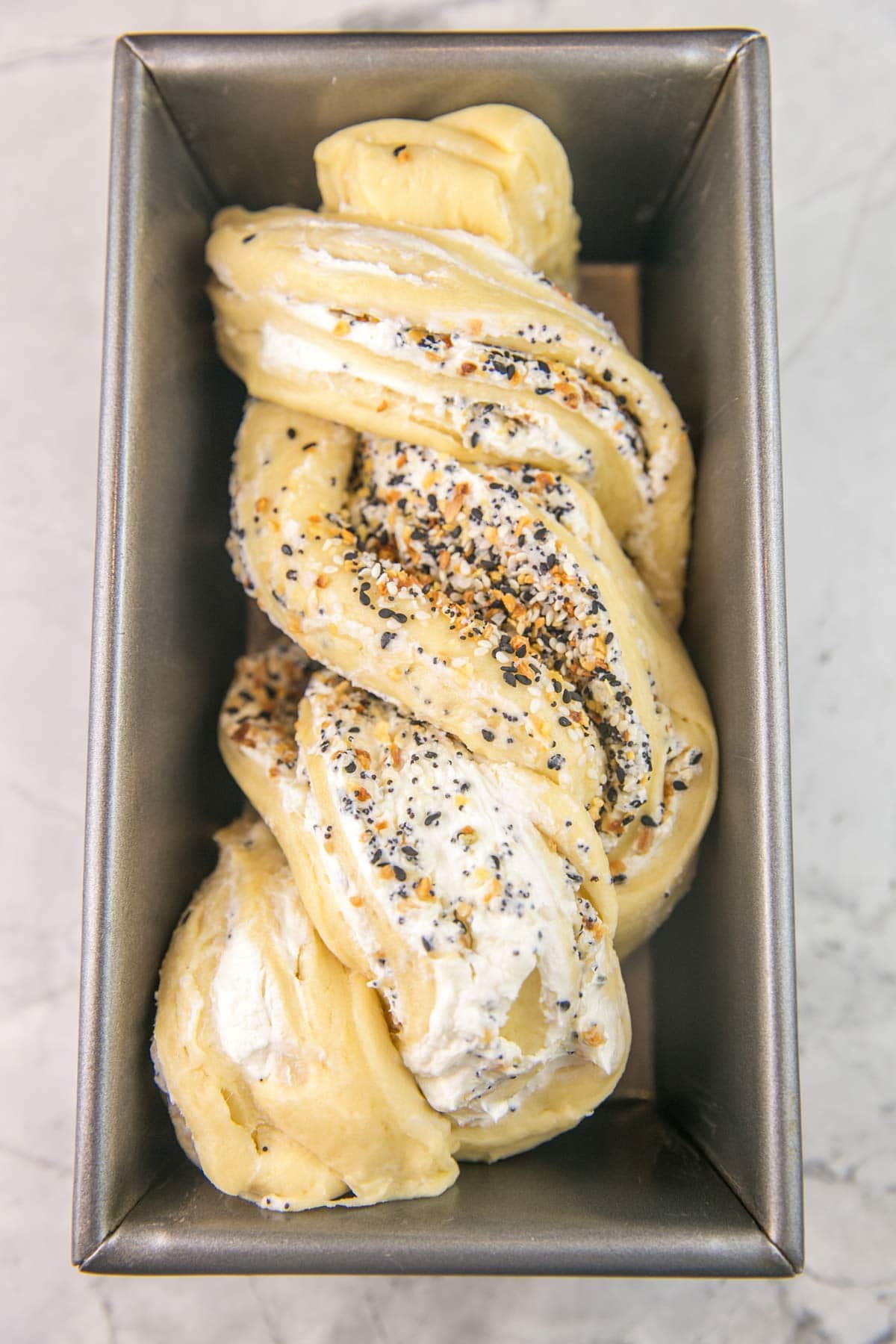 an unbaked twist of savory babka dough in a loaf pan