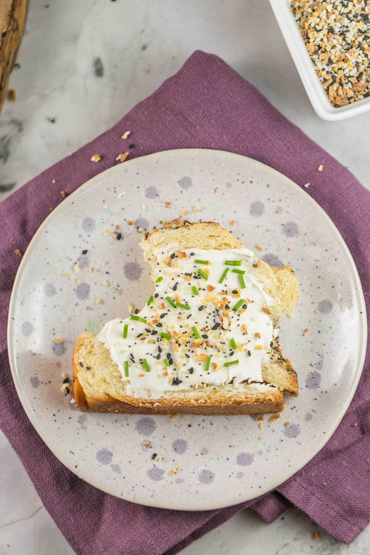 a slice of everything bagel babka spread with cream cheese with a sprinkle of bright green chives