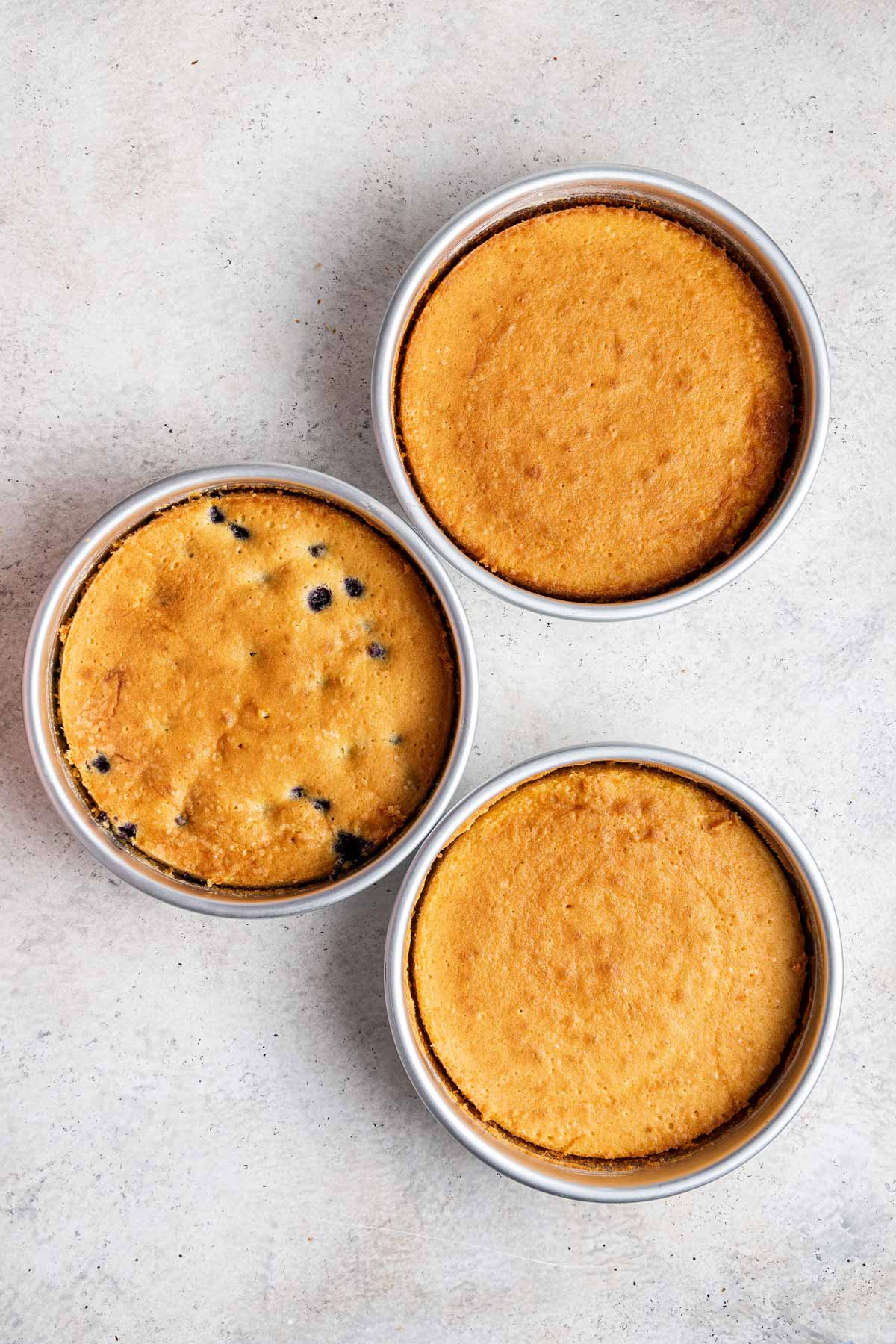 three freshly baked layers of cake still in the cake pans